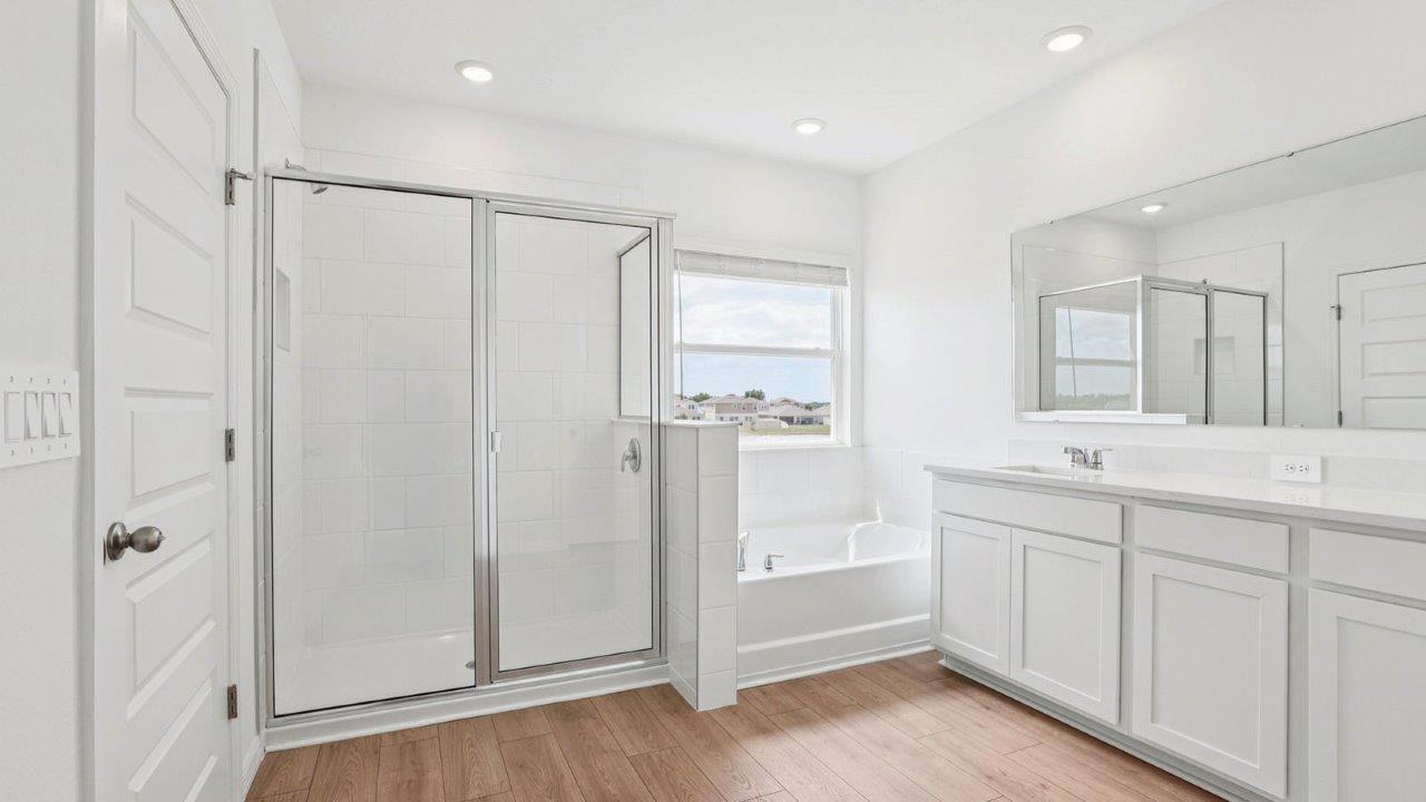 Primary bathroom with a walk in shower and a tub adjacent