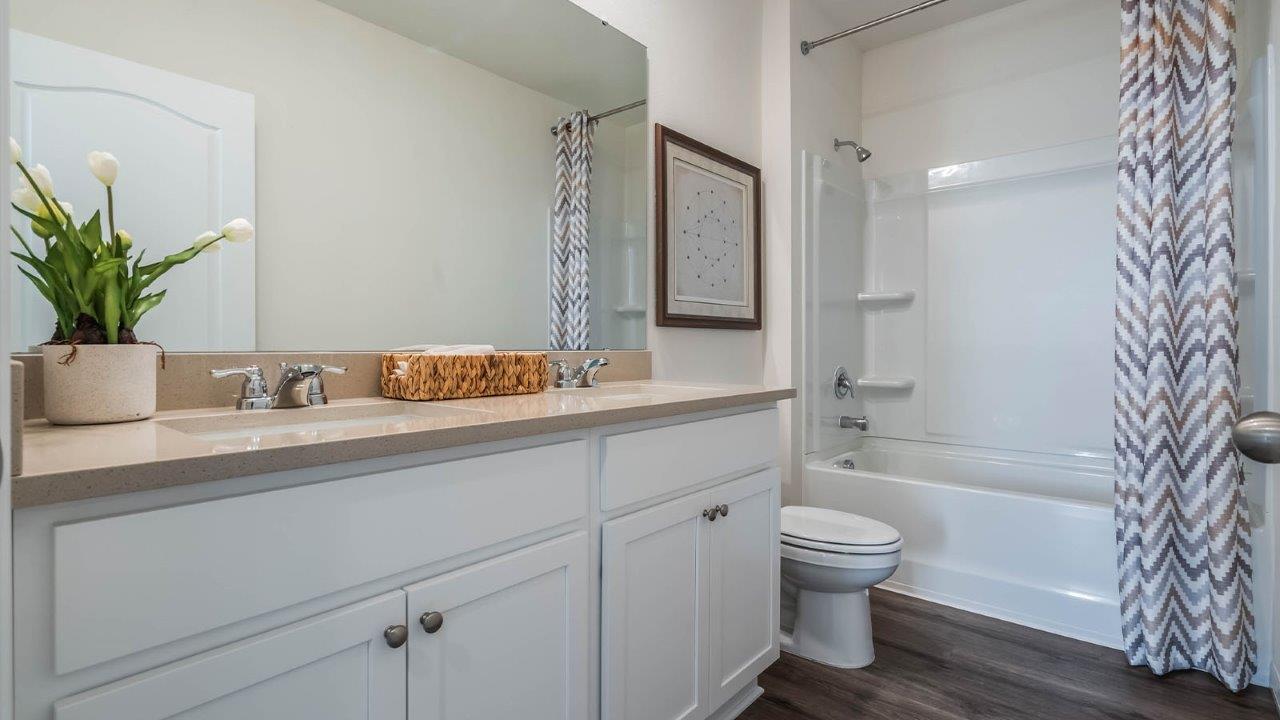 Second-floor guest bathroom with double vanity sinks and tub