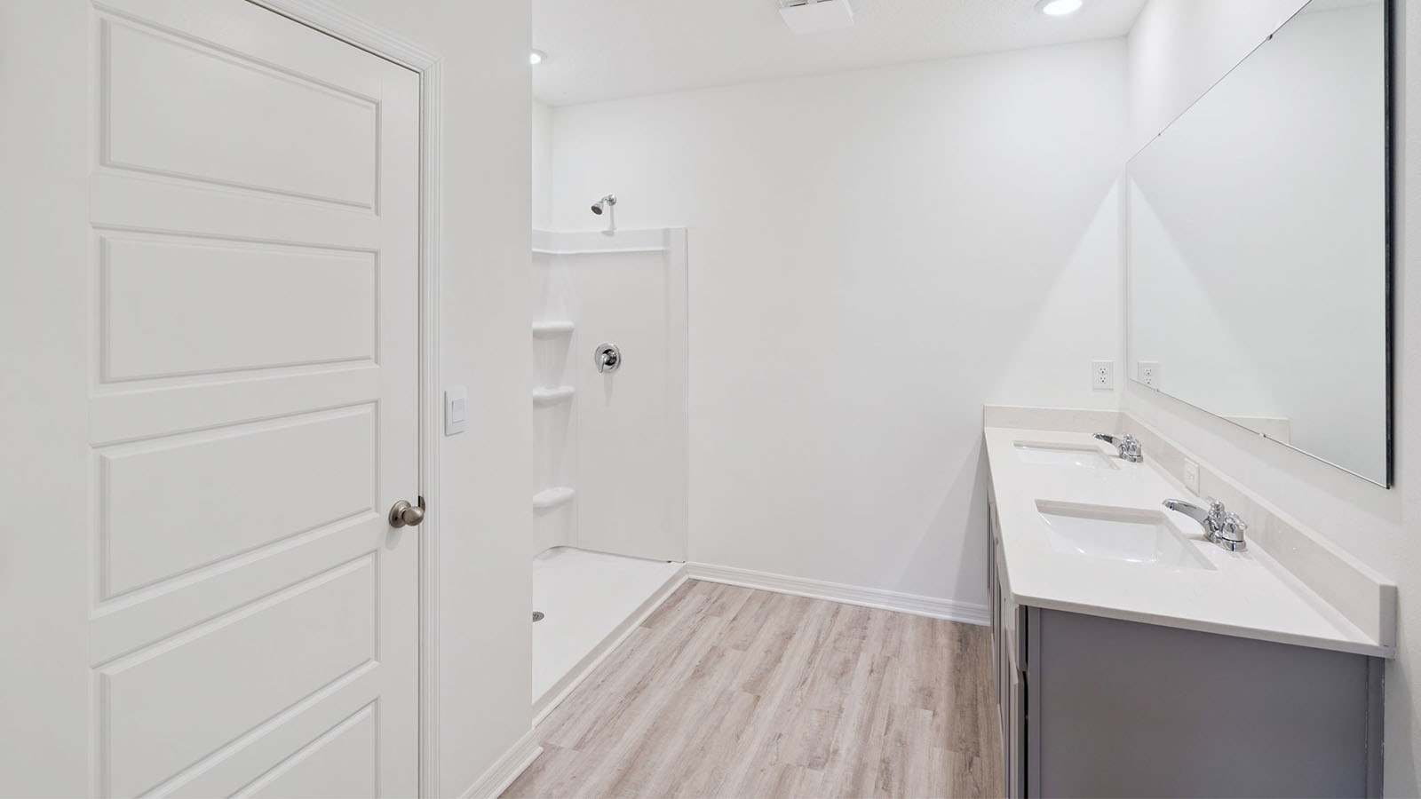 Primary bathroom with luxury vinyl plank flooring, walk in shower, and dual vanity sinks