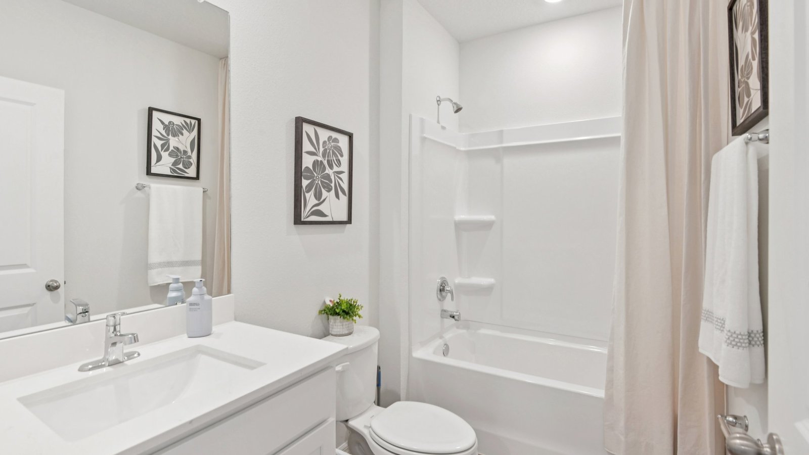Modern bathroom with single bowl sink, quartz vanity, wall mirror, cabinets and toilet.