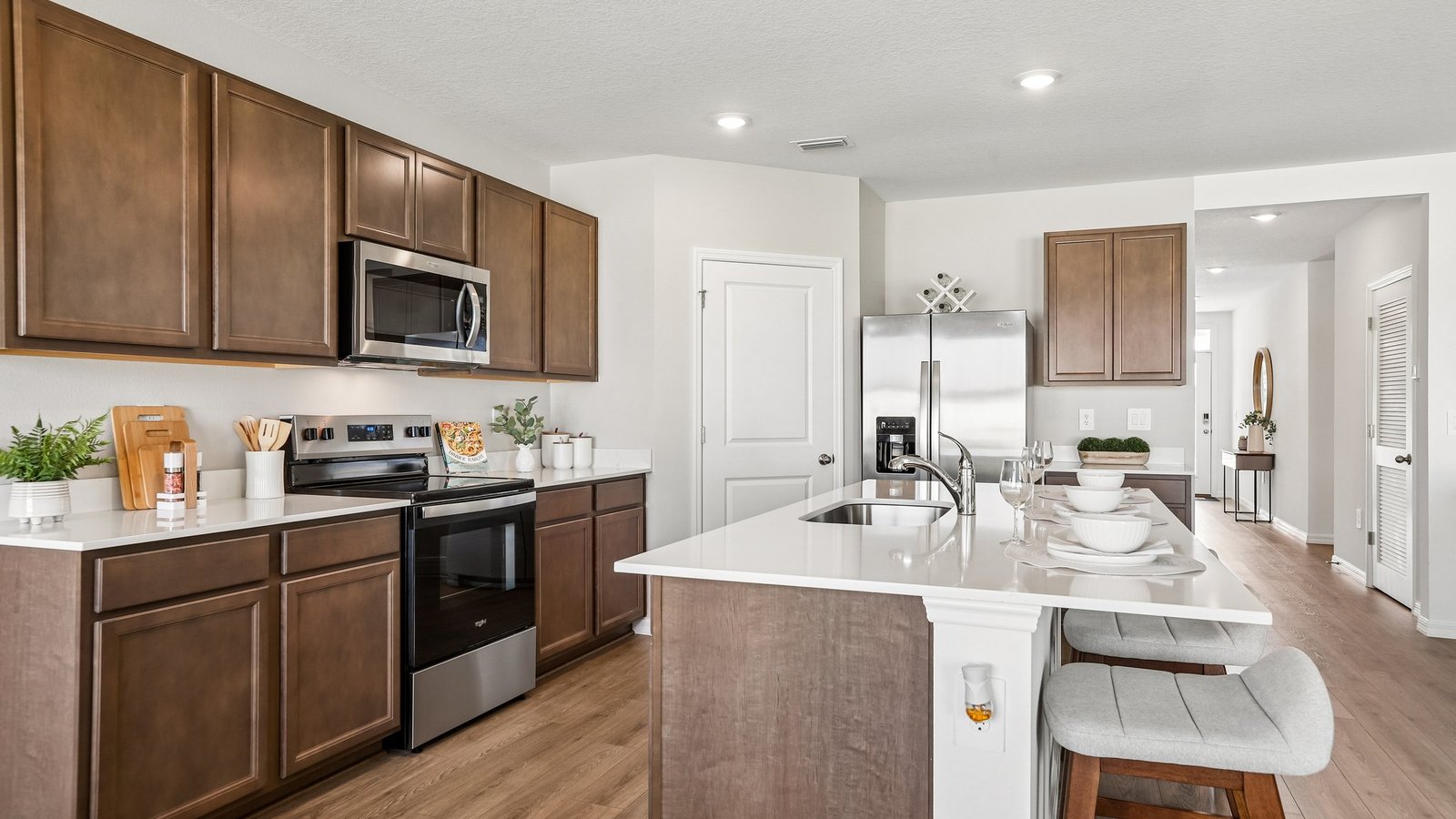 Kitchen with island seating, quartz counters, spacious pantry and stainless-steel appliances.