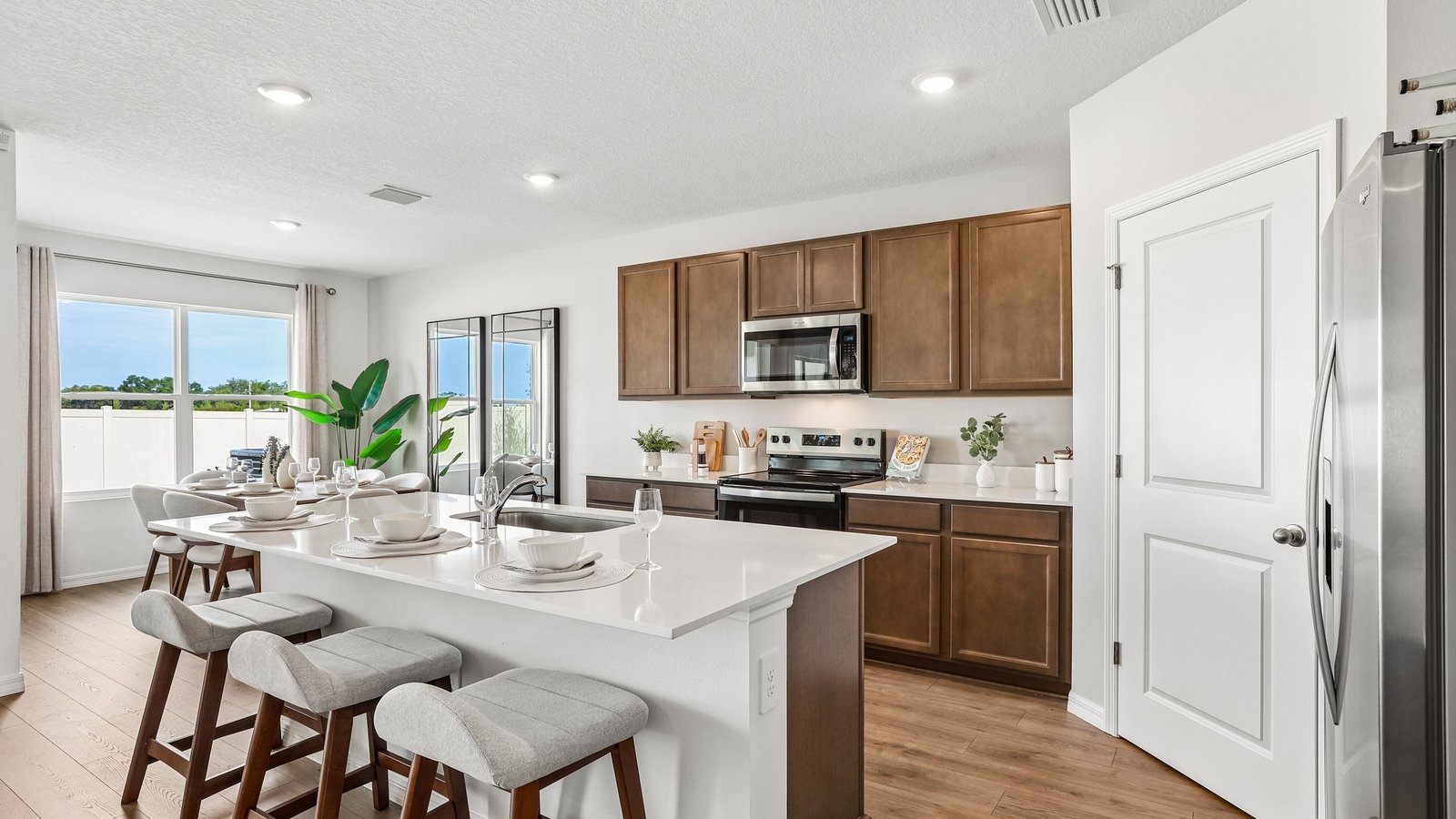 Kitchen with island seating, quartz counters, spacious pantry and stainless-steel appliances.