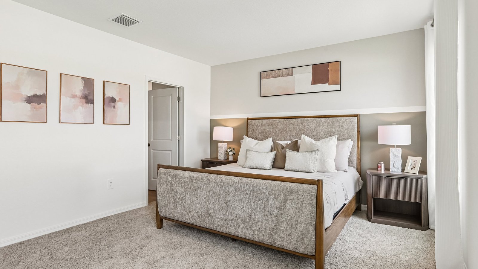 Spacious primary bedroom with king size bed, carpet flooring, natural lighting and a walk in closet.