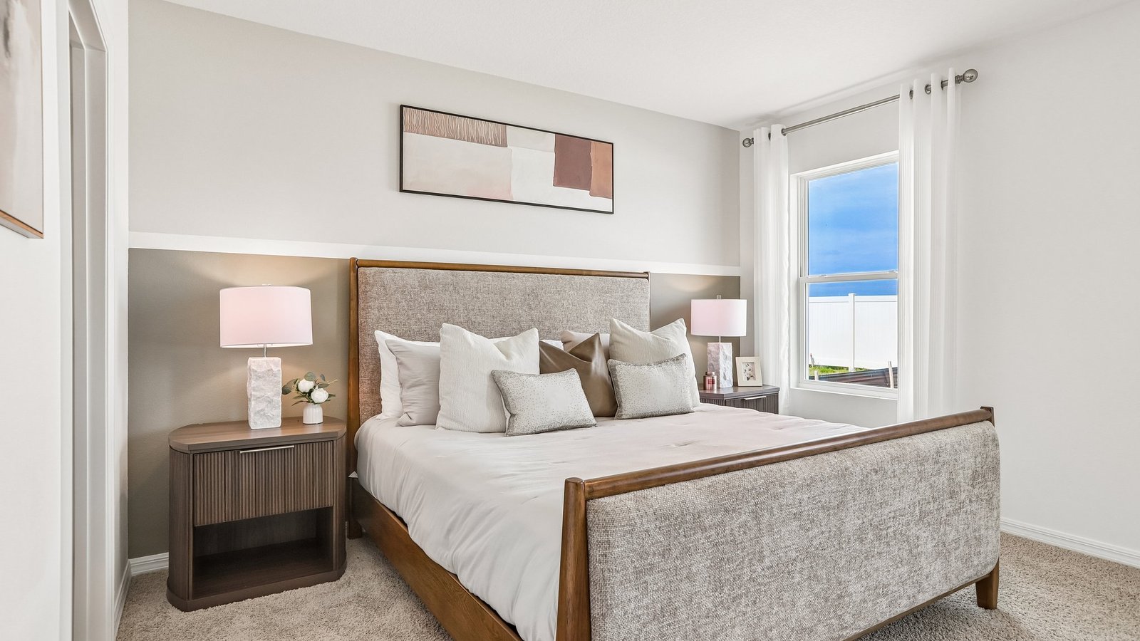 Spacious primary bedroom with king size bed, carpet flooring, natural lighting and a walk in closet.