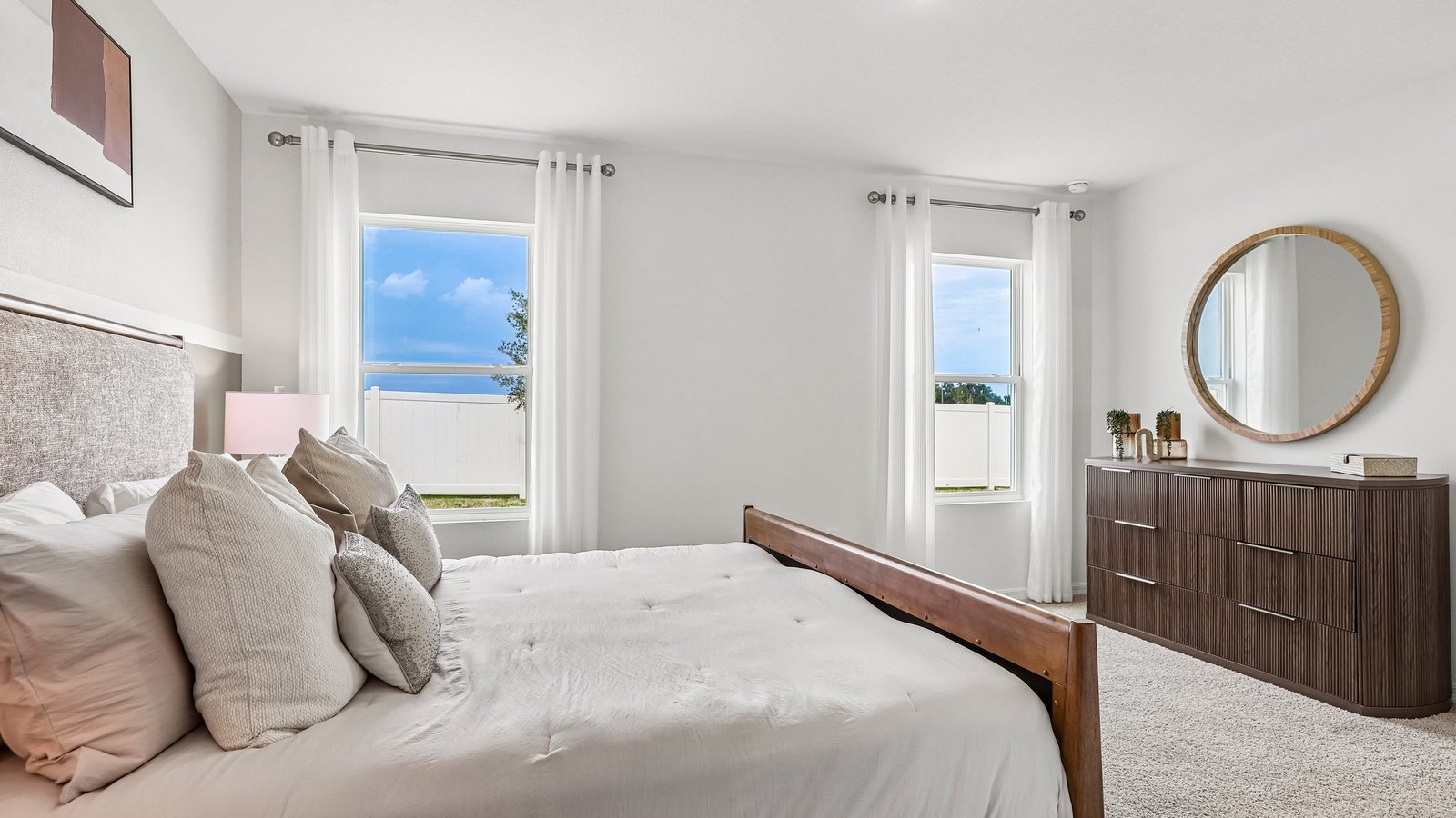 Spacious primary bedroom with king size bed, carpet flooring, natural lighting and a walk in closet.