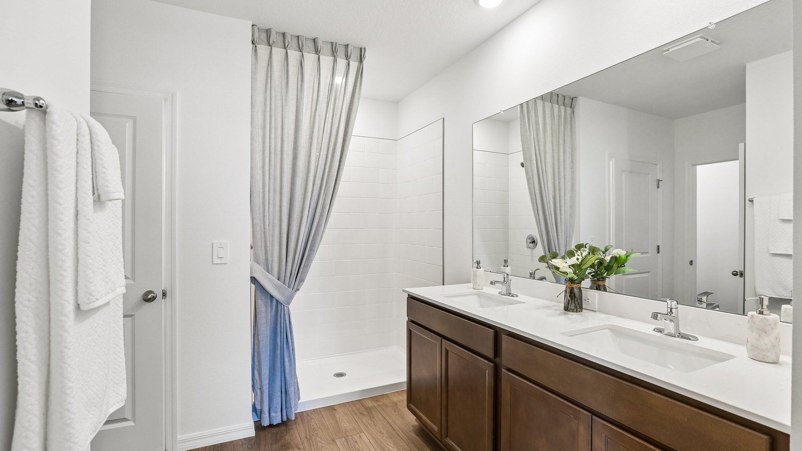 Modern bathroom with double vanity sinks, large wall mirror, cabinets and quartz countertops.