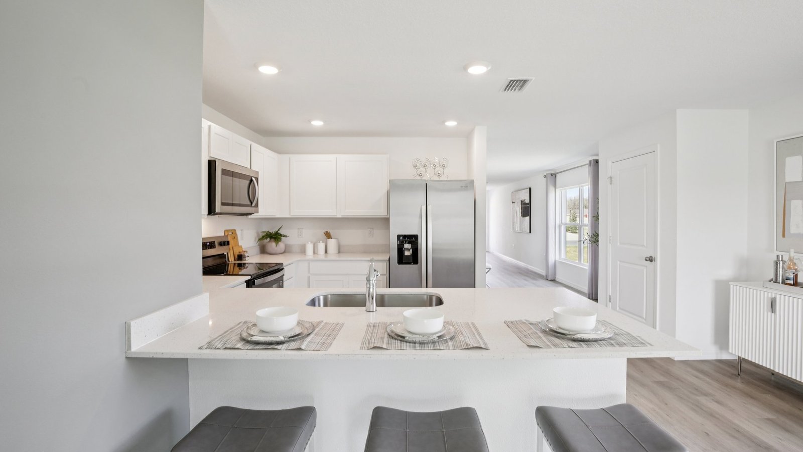 Kitchen with island seating, quartz counters, spacious pantry and stainless-steel appliances.