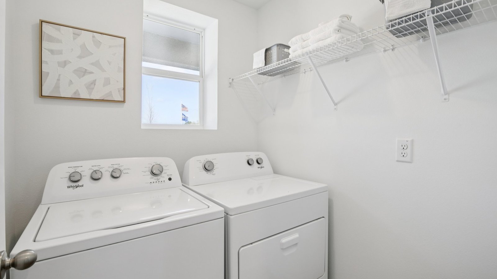 Laundry room with washer and dryer hookups and wall shelving.