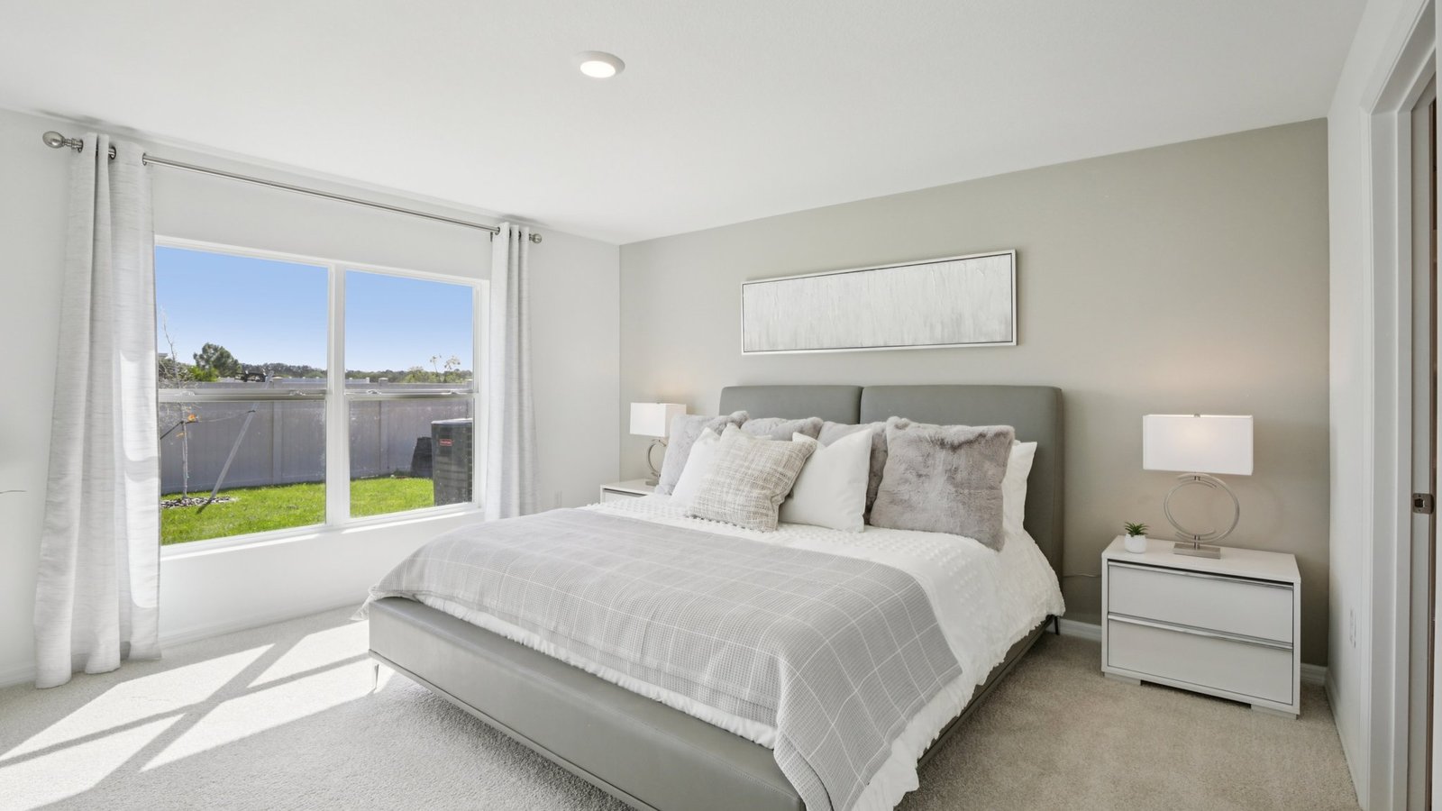 Spacious primary bedroom with king size bed, carpet flooring, natural lighting and a walk in closet.