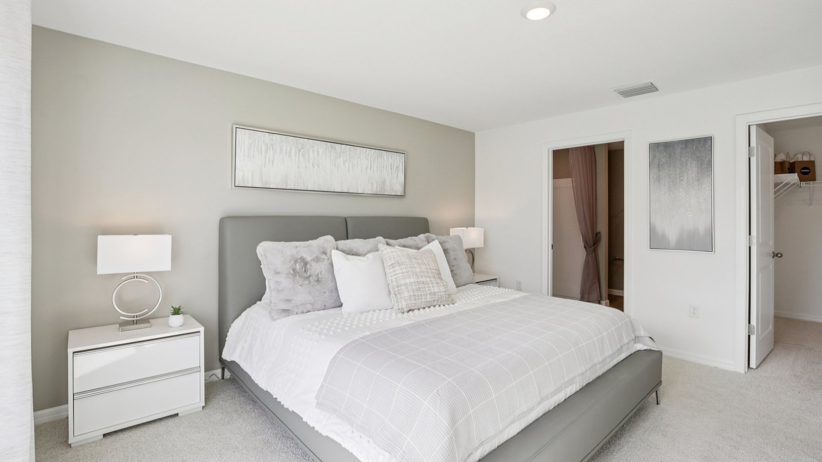 Spacious primary bedroom with king size bed, carpet flooring, natural lighting and a walk in closet.