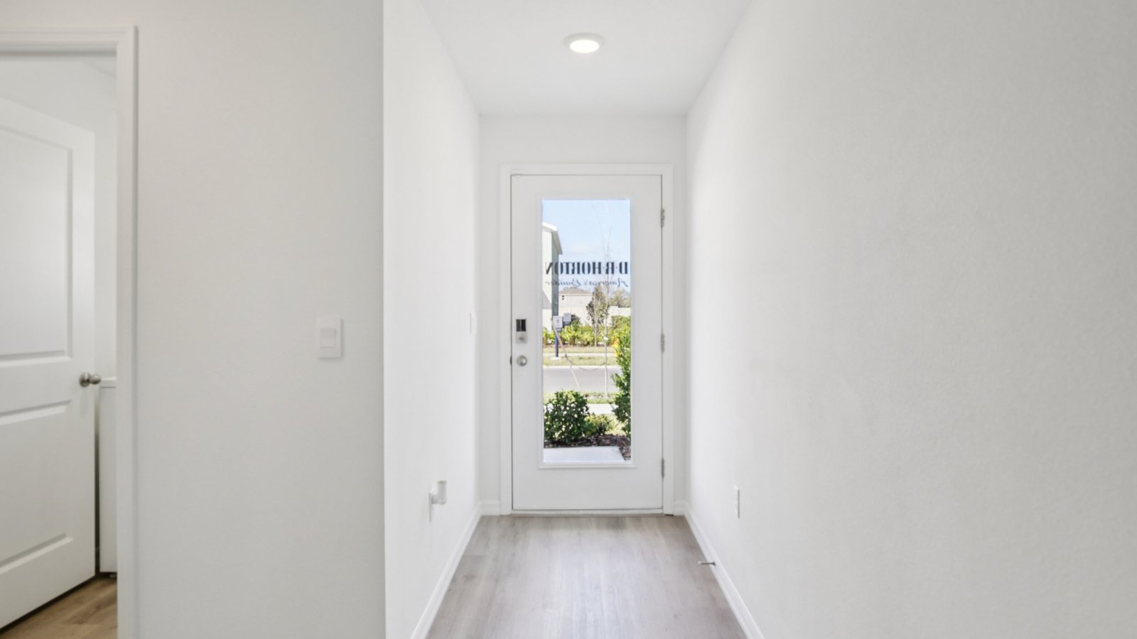 Home entry way thru the front door with LVP flooring and a view to the living space.