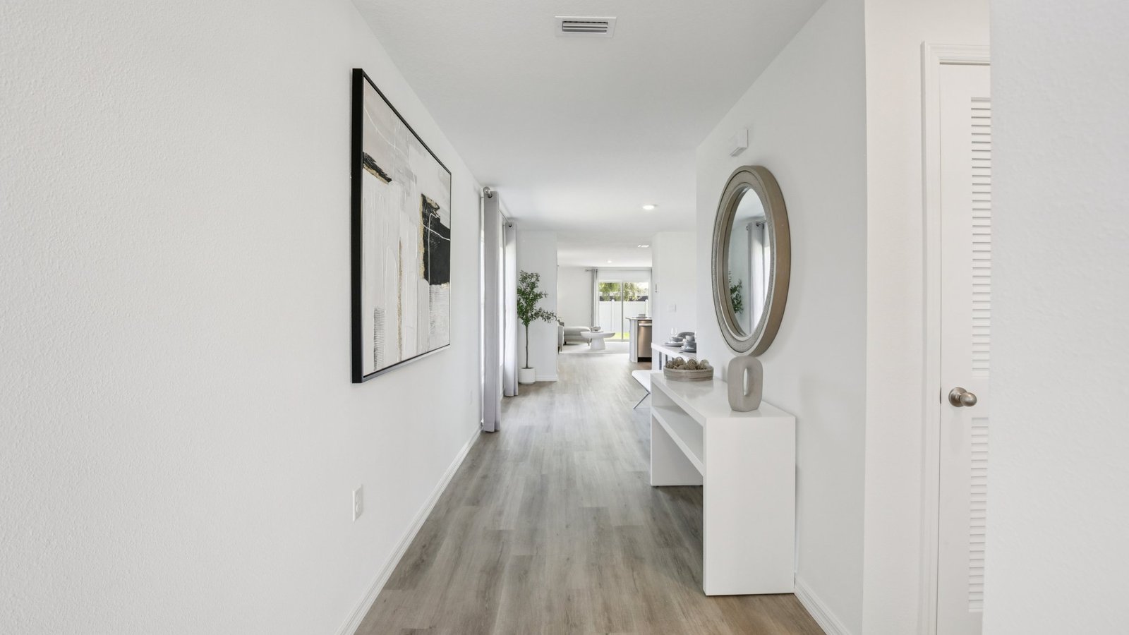 Home entry way thru the front door with LVP flooring and a view to the living space.