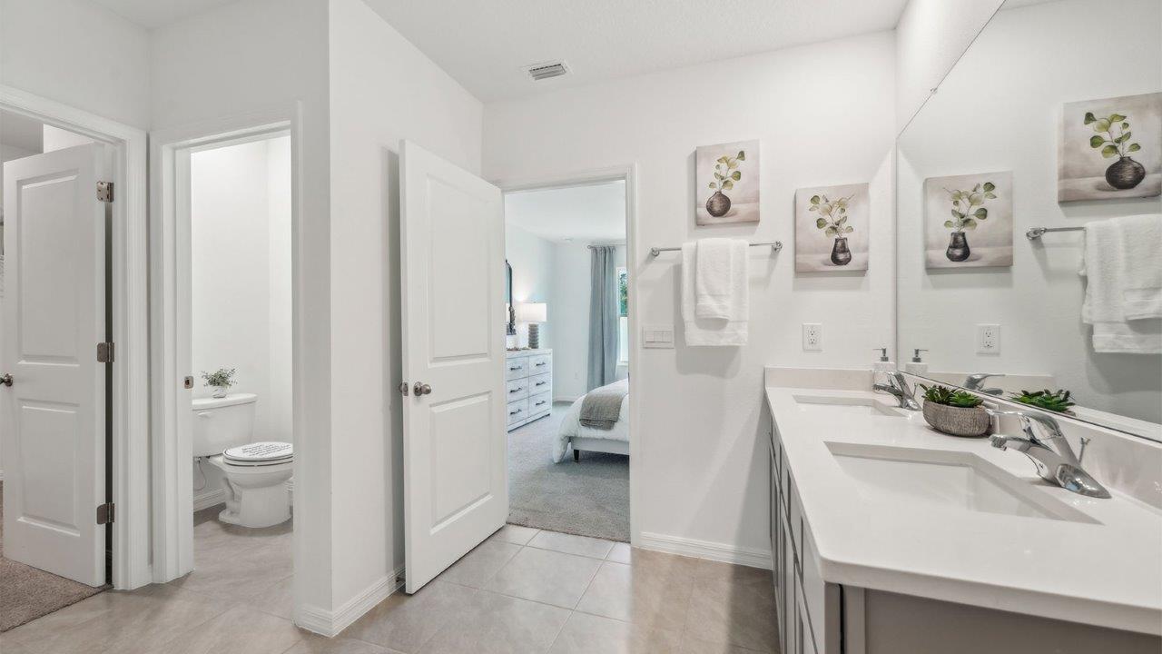 Modern bathroom with double vanity, large wall mirror, cabinets and quartz countertops along with walk-in shower.