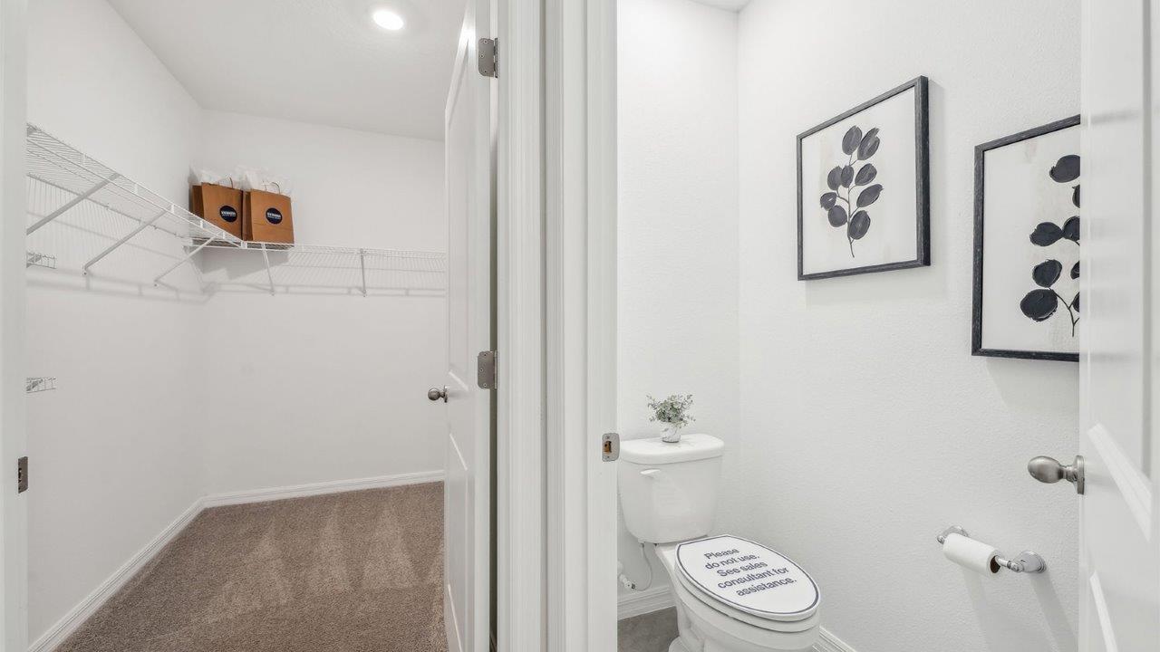 Bathroom with double vanity, large wall mirror, cabinets and quartz countertops along with private lavatory and walk-in closet.