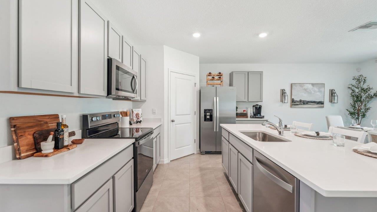 Kitchen with island seating, quartz counters, spacious pantry and stainless-steel appliances.