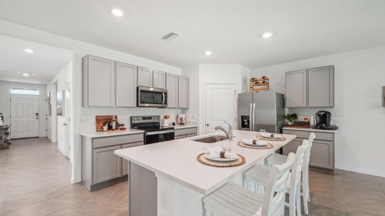 Kitchen with island seating, quartz counters, spacious pantry and stainless-steel appliances.