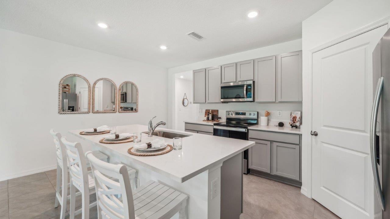 Kitchen with island seating, quartz counters, spacious pantry and stainless-steel appliances.