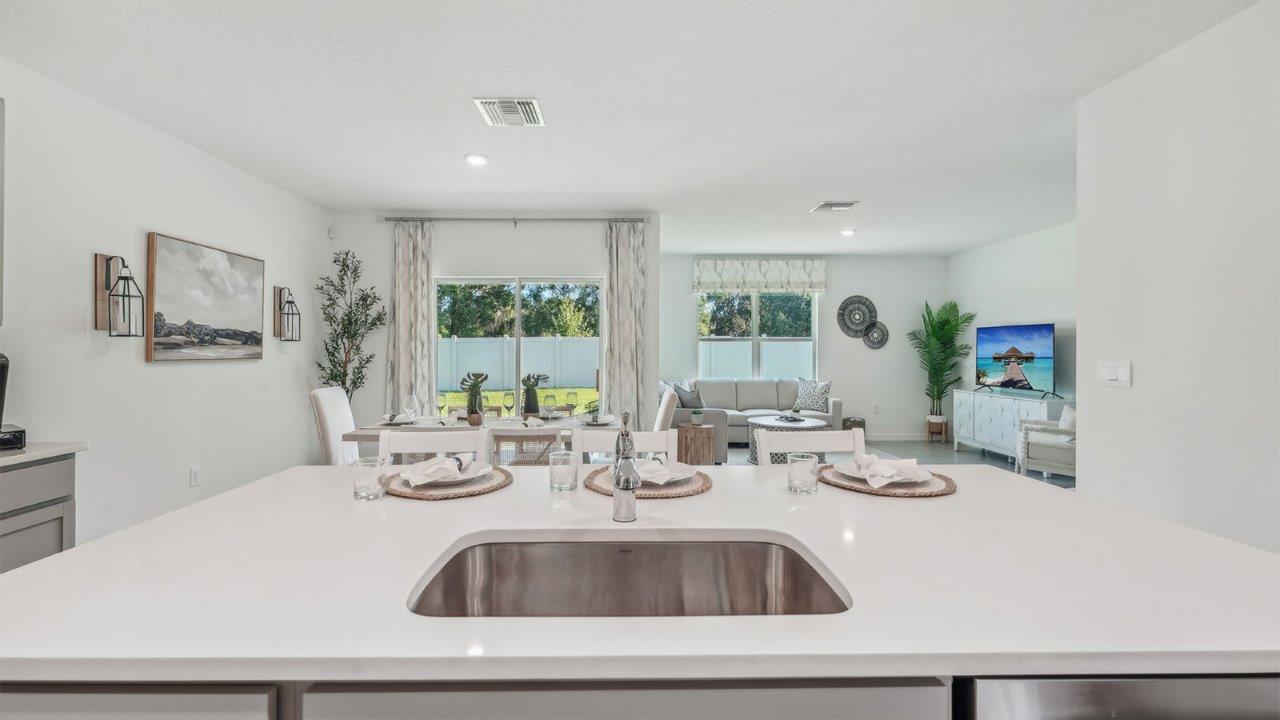 Kitchen with island seating, quartz counters, spacious pantry and stainless-steel appliances.