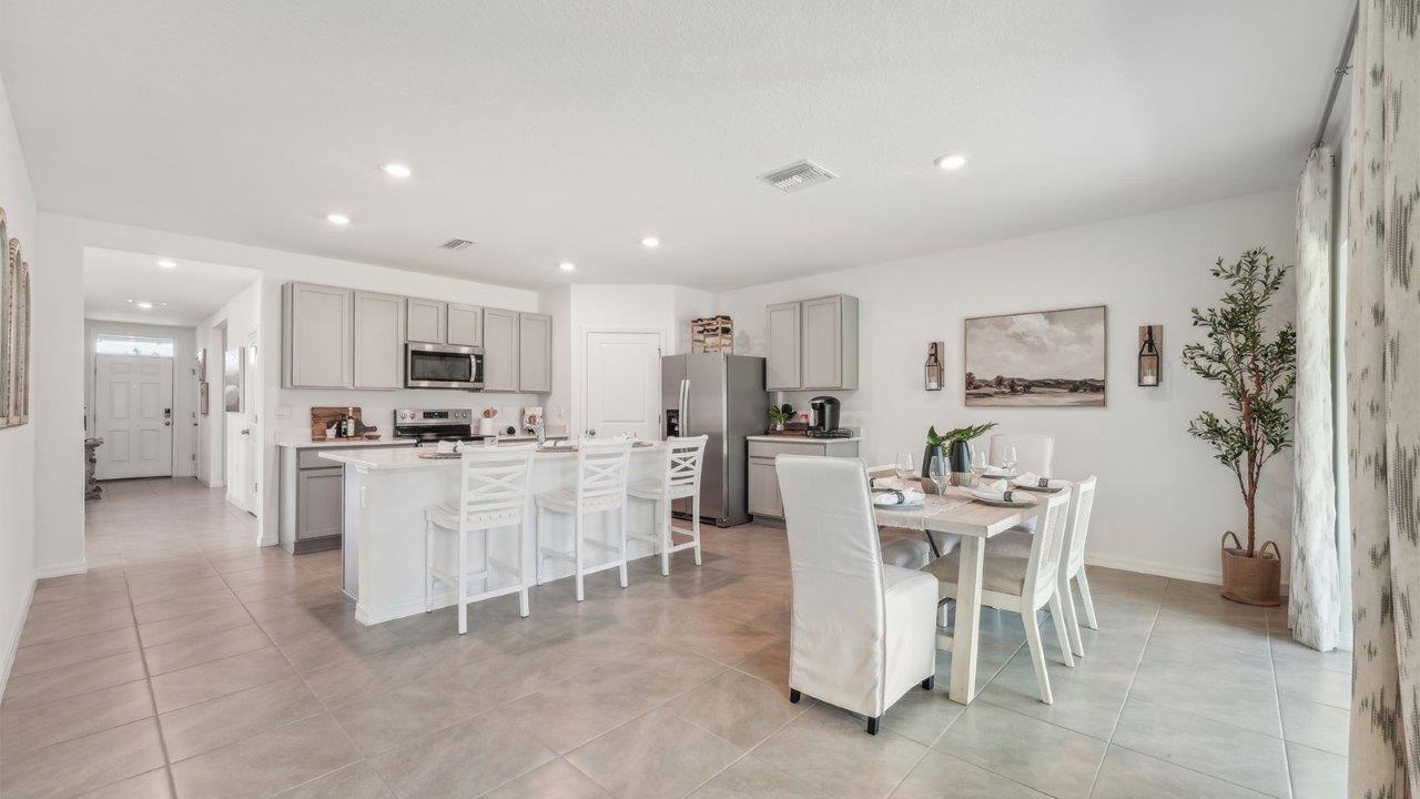 Dining room adjacent to the kitchen with table, chairs and tile flooring.