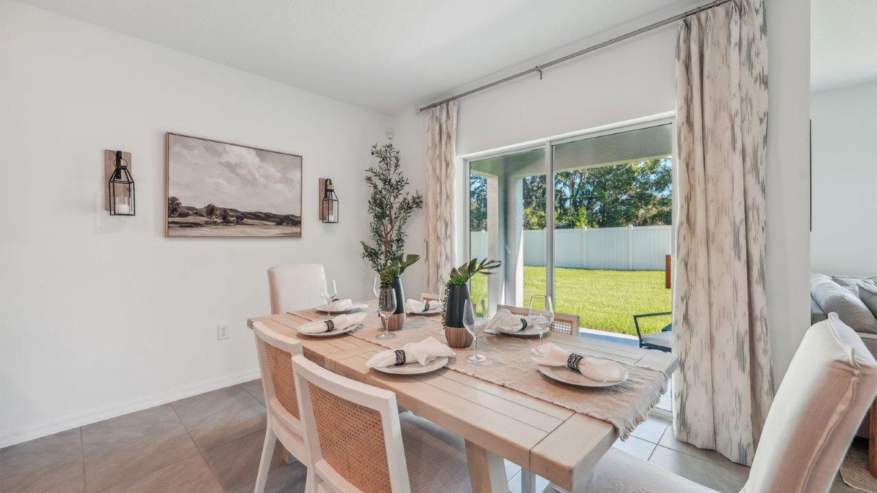 Dining room adjacent to the kitchen with table, chairs and tile flooring.
