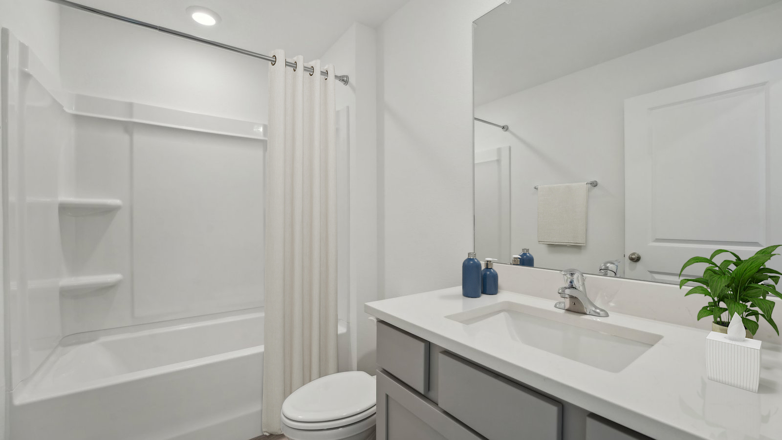 Modern bathroom with single bowl sink, quartz vanity, wall mirror, cabinets and toilet.