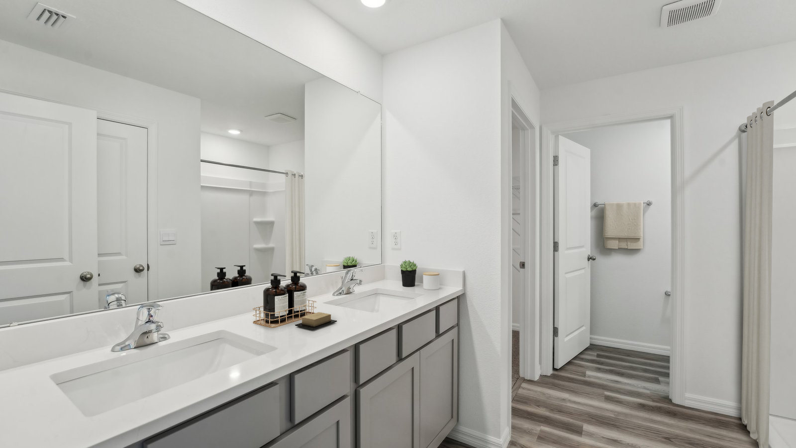 Modern bathroom with double vanity sinks, large wall mirror, cabinets and quartz countertops.