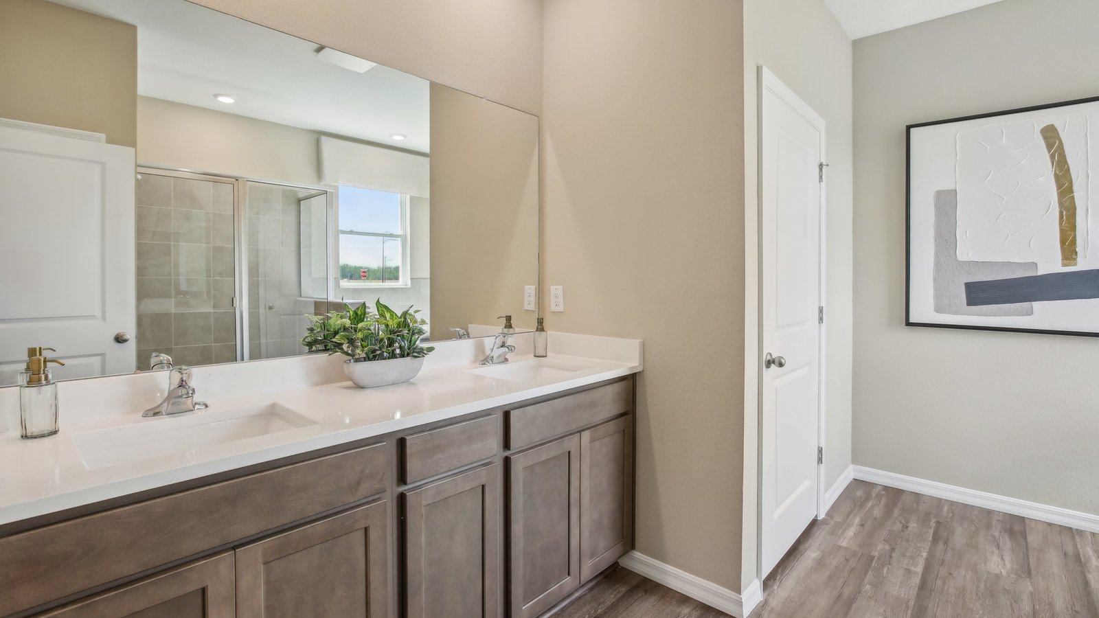 Modern bathroom with double vanity sinks, large wall mirror, cabinets and quartz countertops.