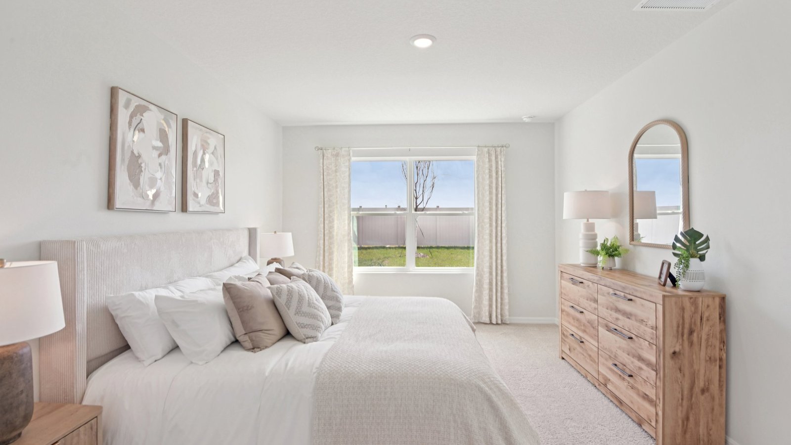 Spacious primary bedroom with king size bed, carpet flooring, natural lighting and a walk in closet.