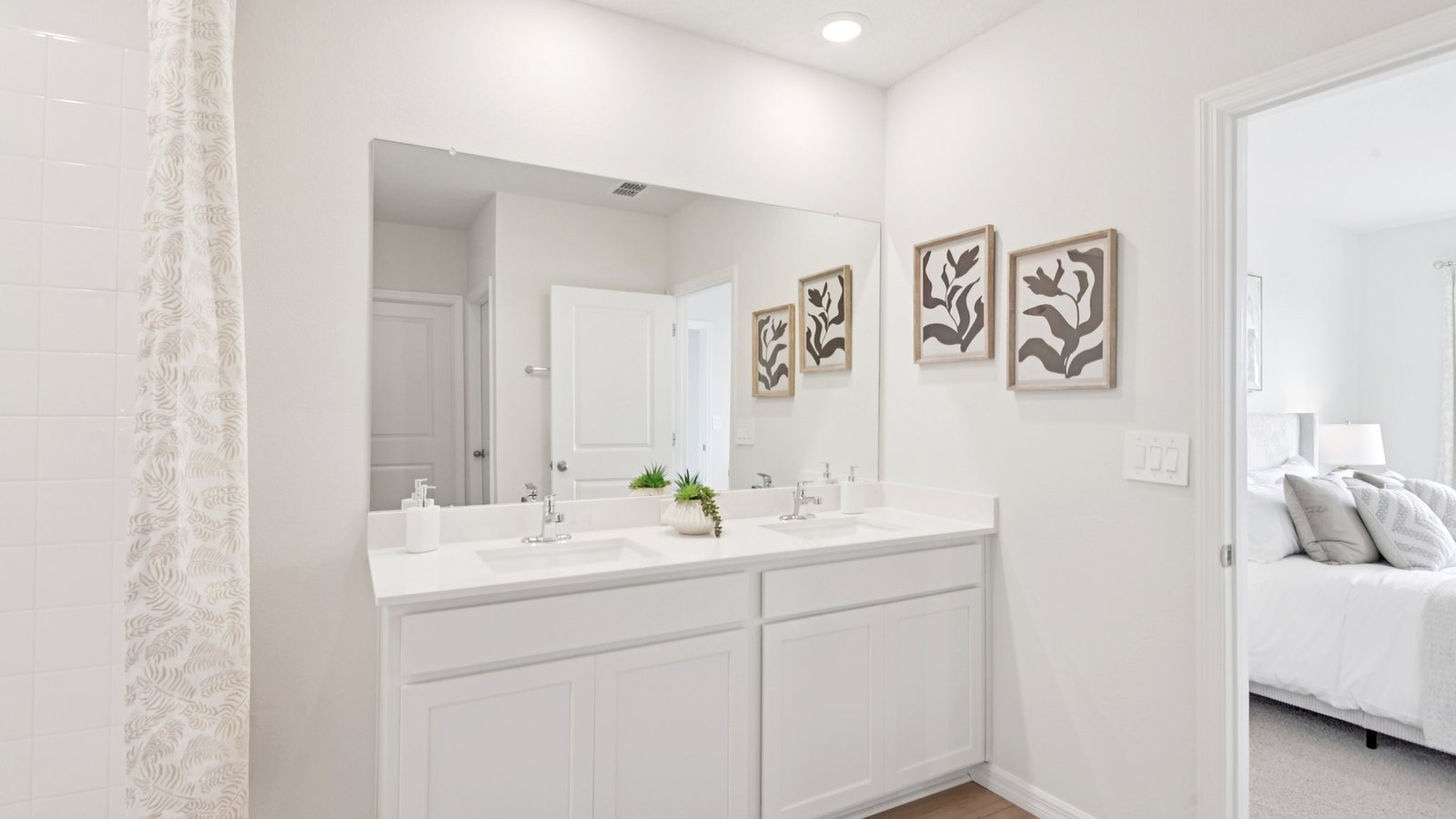 Modern bathroom with double vanity sinks, large wall mirror, cabinets and quartz countertops.