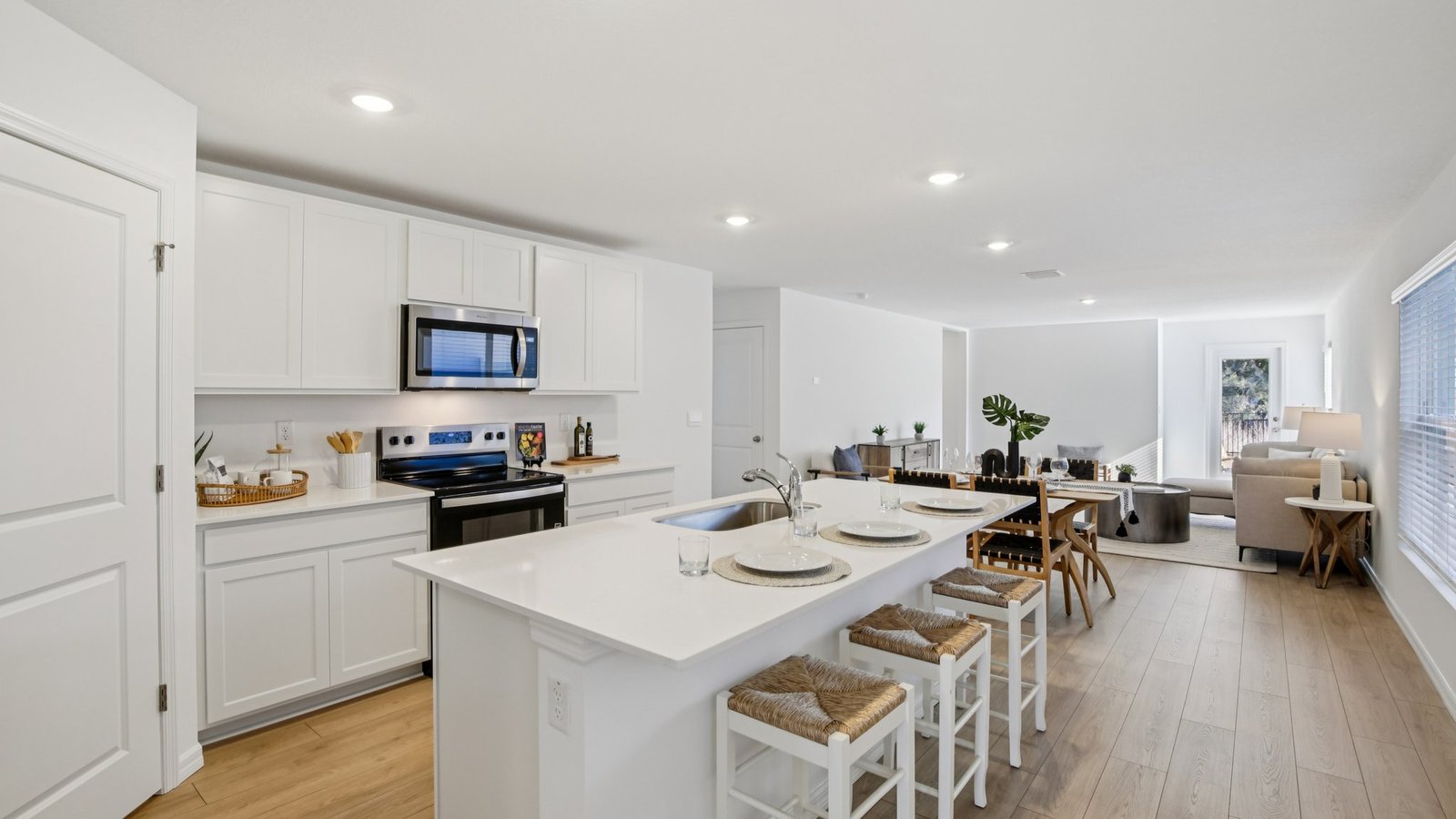 Kitchen with island seating, quartz counters, spacious pantry and stainless-steel appliances.