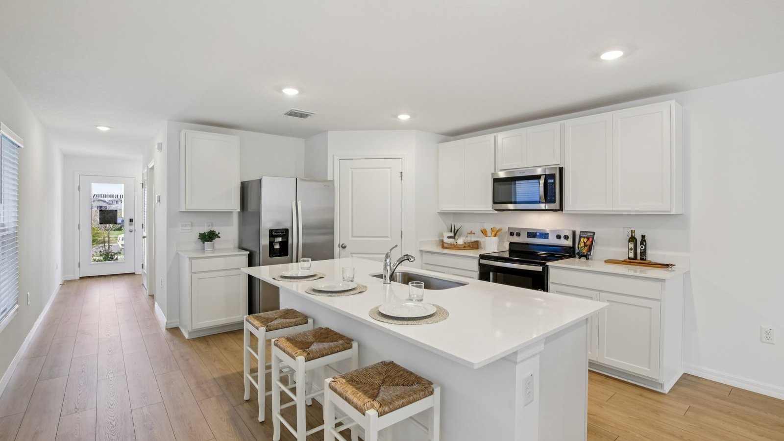 Kitchen with island seating, quartz counters, spacious pantry and stainless-steel appliances.