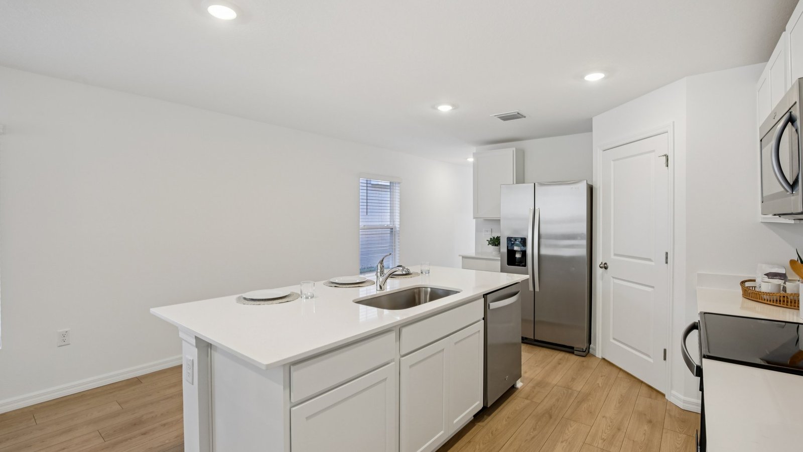 Kitchen with island seating, quartz counters, spacious pantry and stainless-steel appliances.