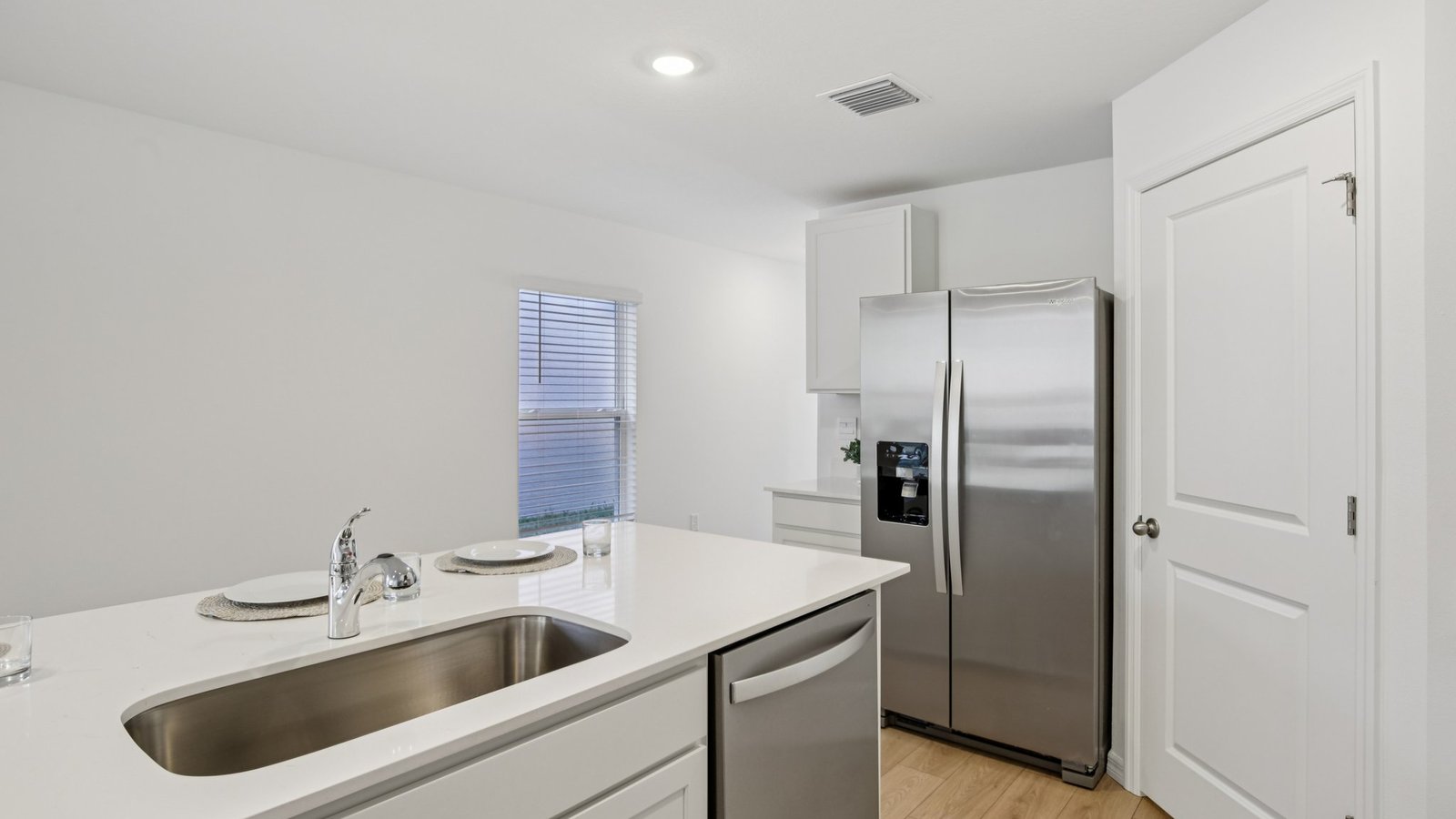 Kitchen with island seating, quartz counters, spacious pantry and stainless-steel appliances.