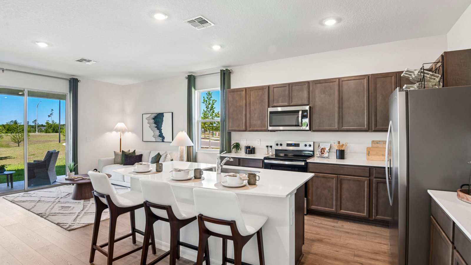Kitchen with island seating, quartz counters, spacious pantry and stainless-steel appliances.