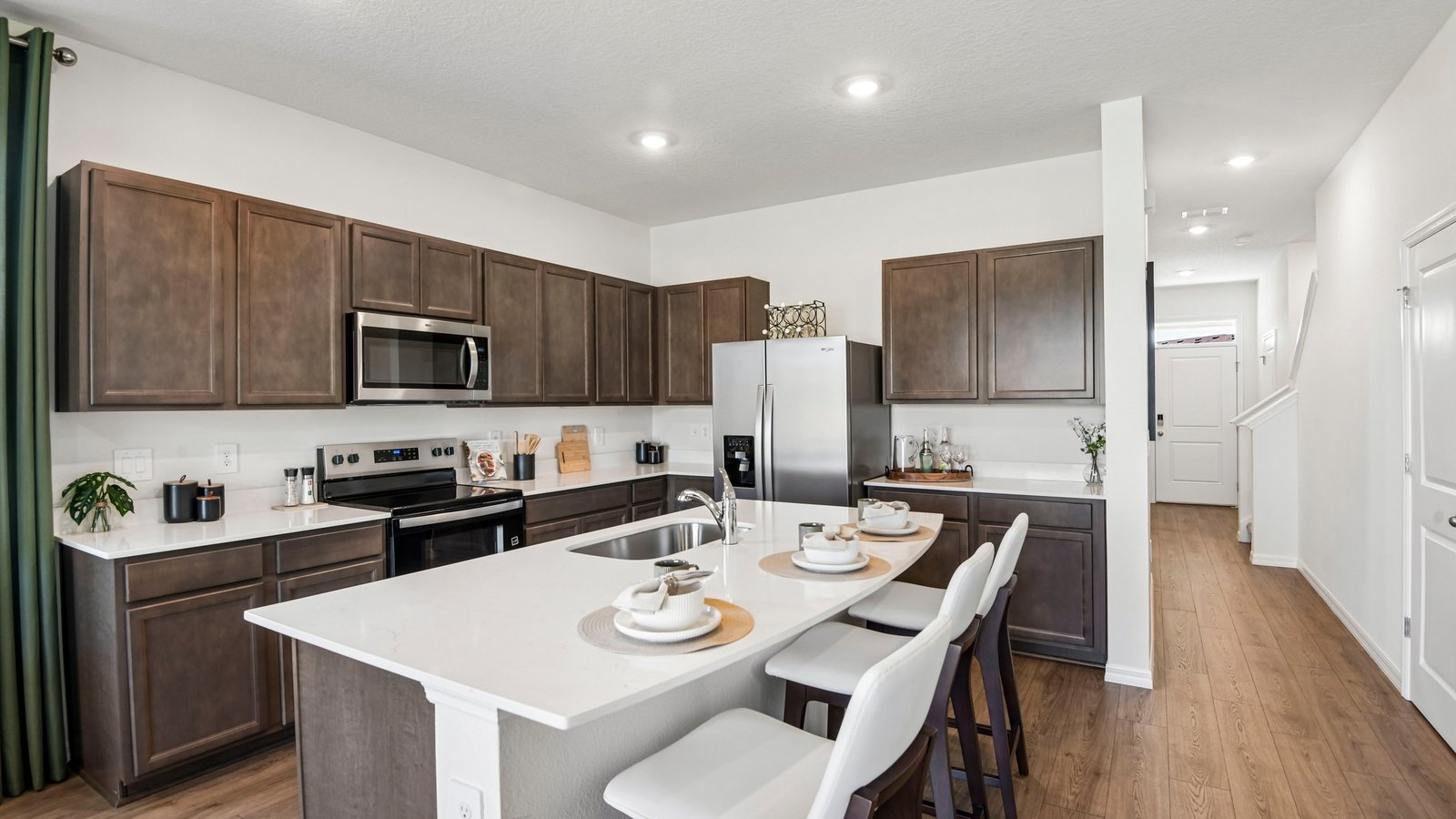 Kitchen with island seating, quartz counters, spacious pantry and stainless-steel appliances.