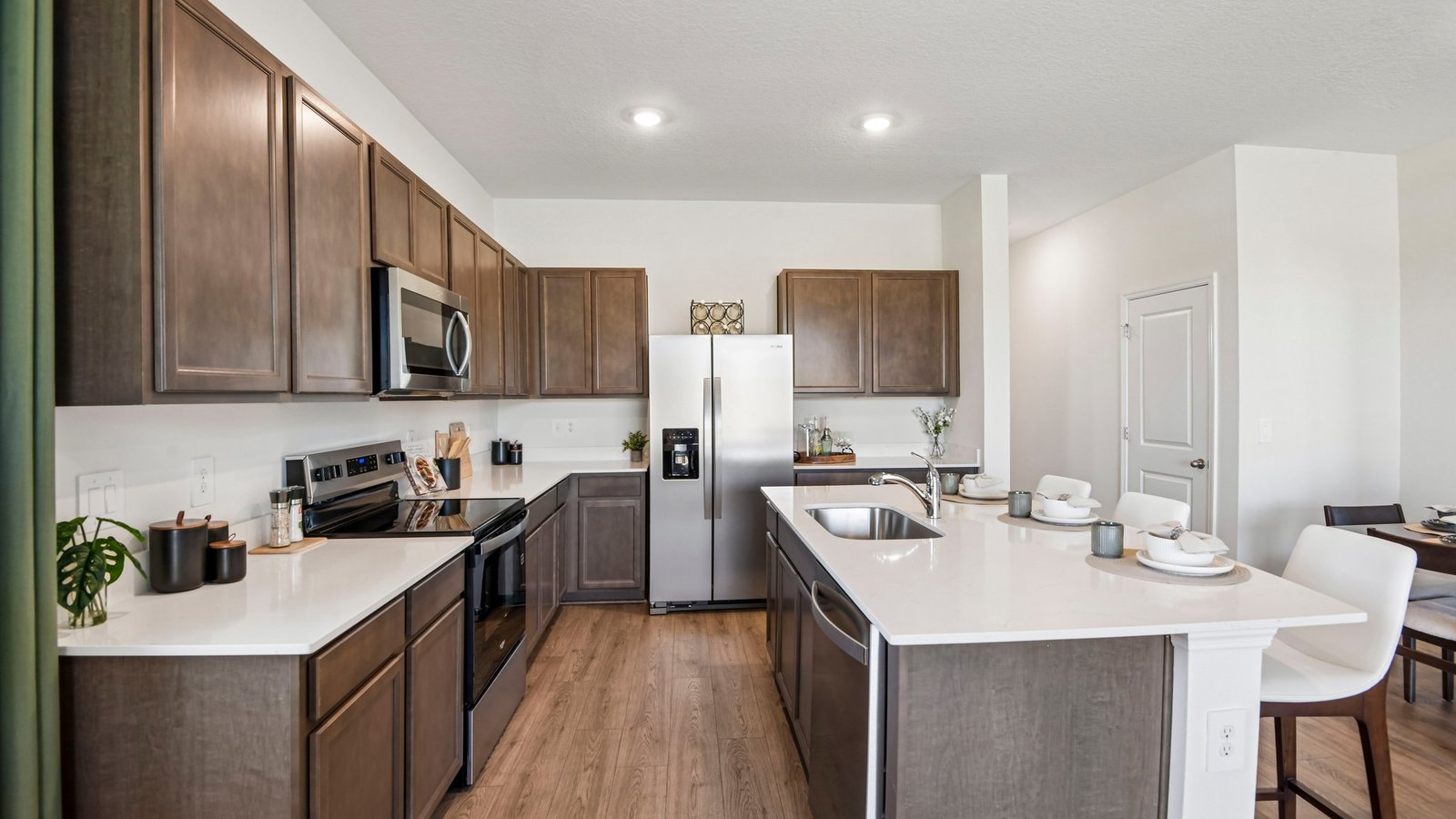 Kitchen with island seating, quartz counters, spacious pantry and stainless-steel appliances.