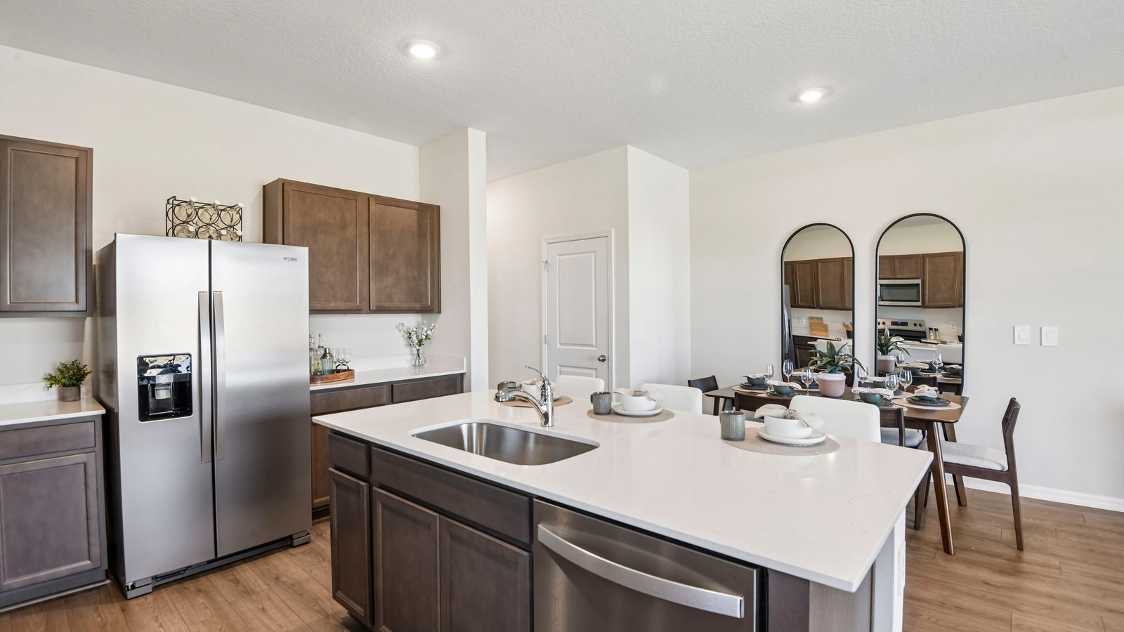 Kitchen with island seating, quartz counters, spacious pantry and stainless-steel appliances.