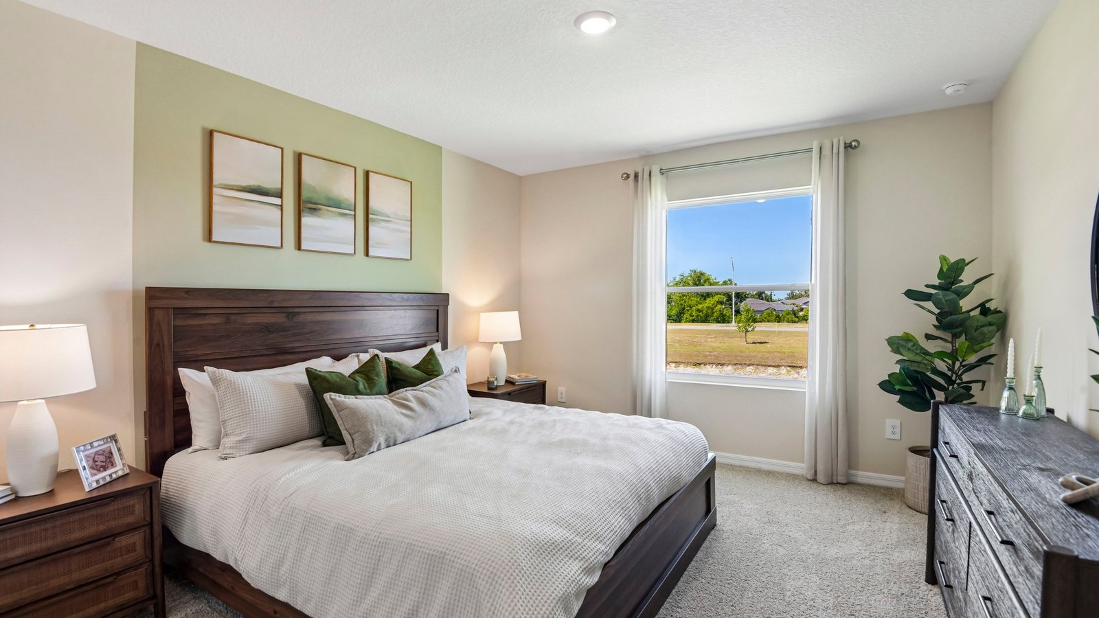 Spacious primary bedroom with king size bed, carpet flooring, natural lighting and a walk in closet.