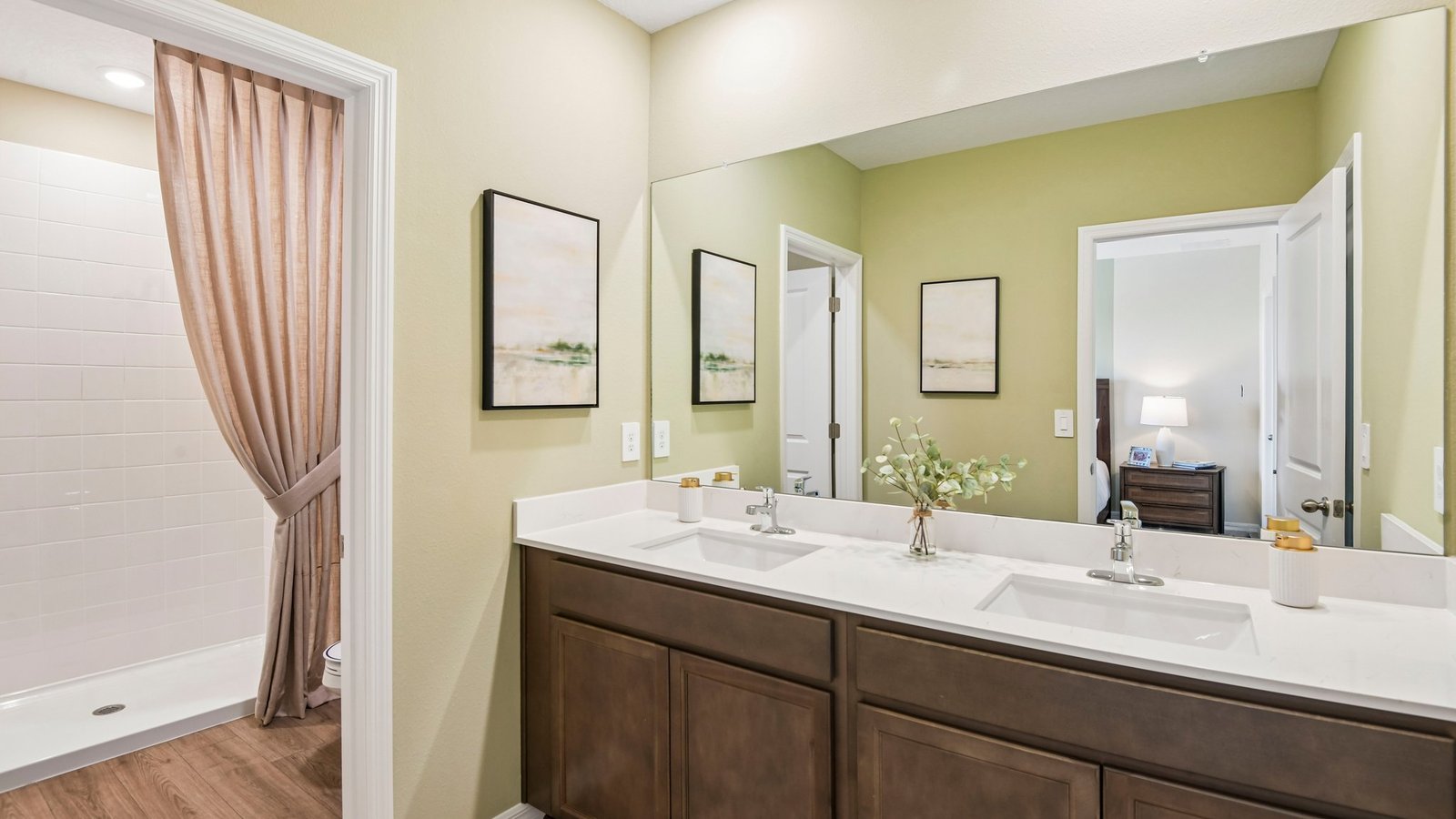 Modern bathroom with double vanity sinks, large wall mirror, cabinets and quartz countertops.