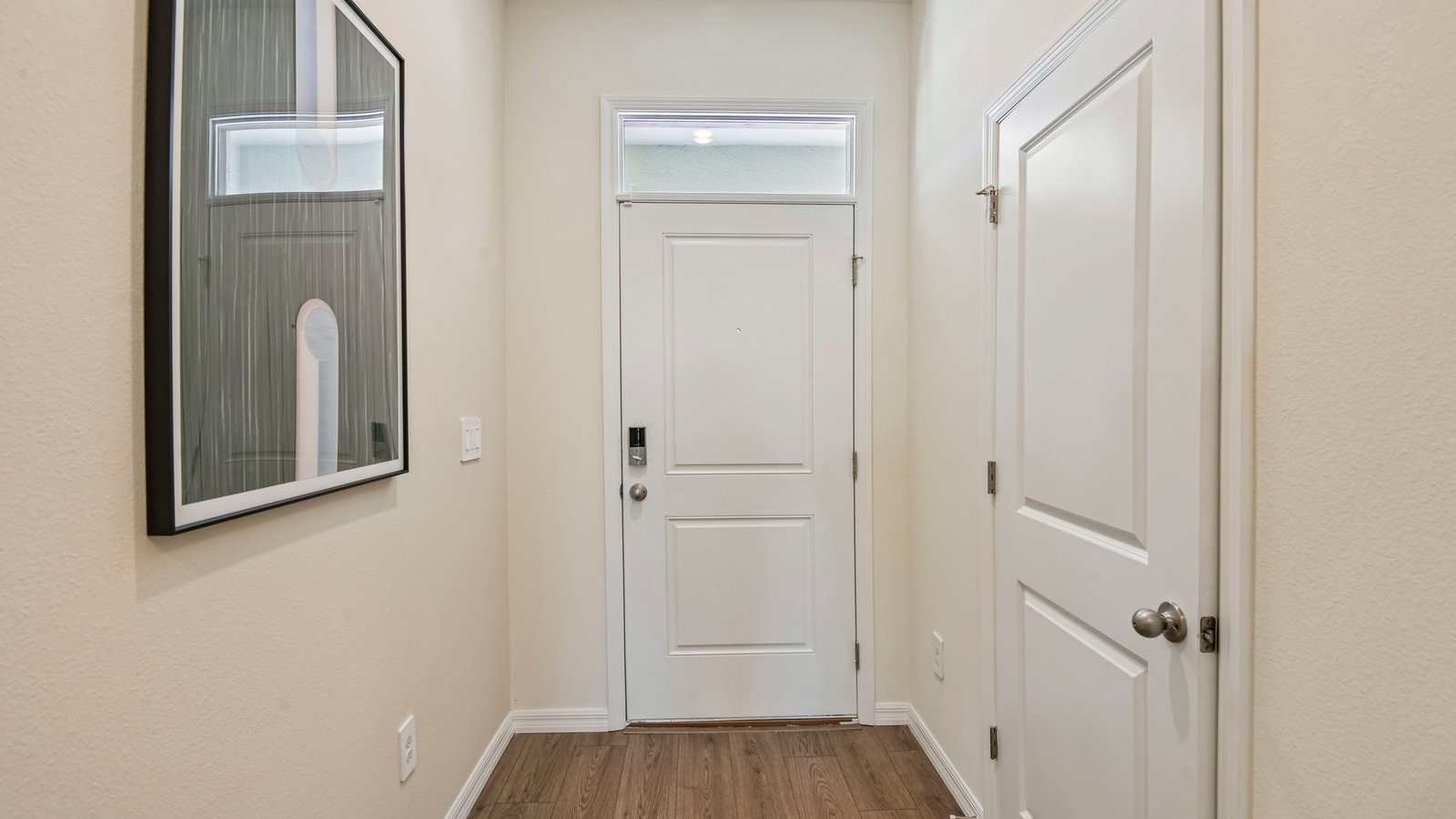 Home entry way thru the front door with LVP flooring and a view to the living space.