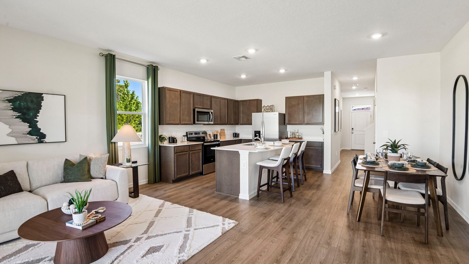 Kitchen with island seating, quartz counters, spacious pantry and stainless-steel appliances.