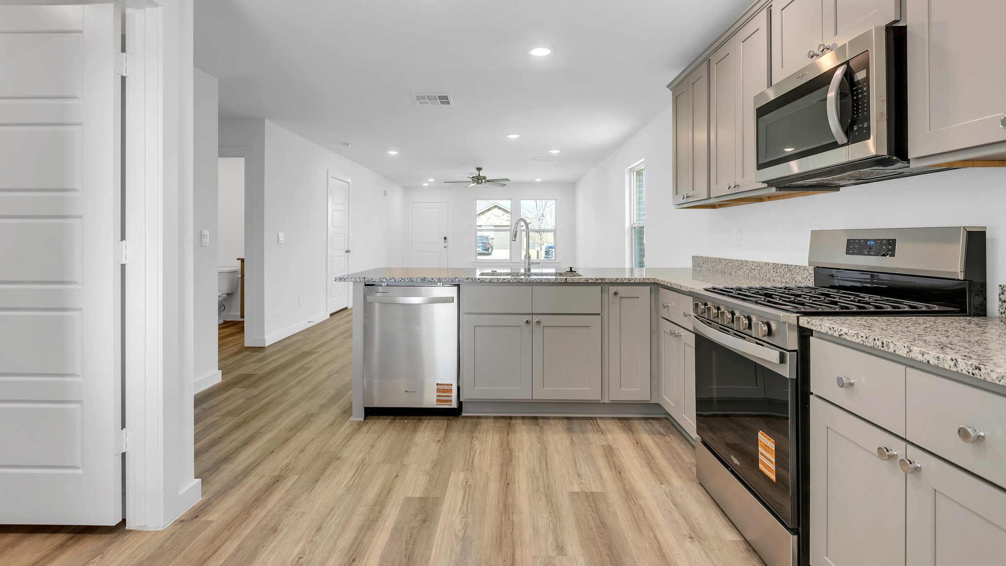 Open concept kitchen with stainless steel appliances, shaker style cabinets, and elevated finishes