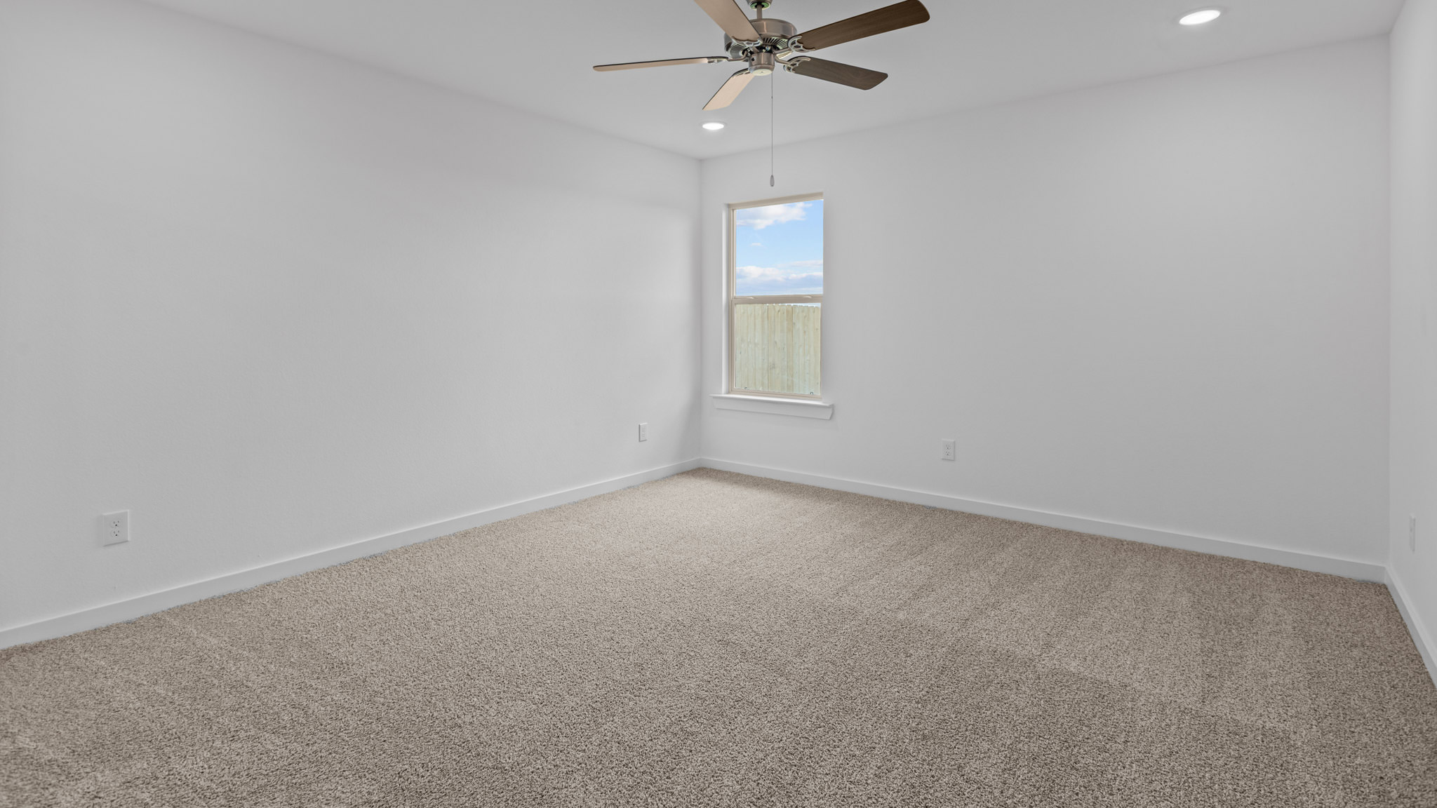 Primary bedroom with plush carpet floors and light allowing window