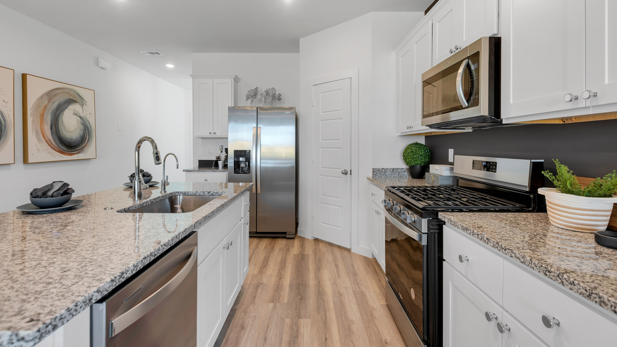 Open concept kitchen with stainless steel appliances, shaker style cabinets, and elevated finishes