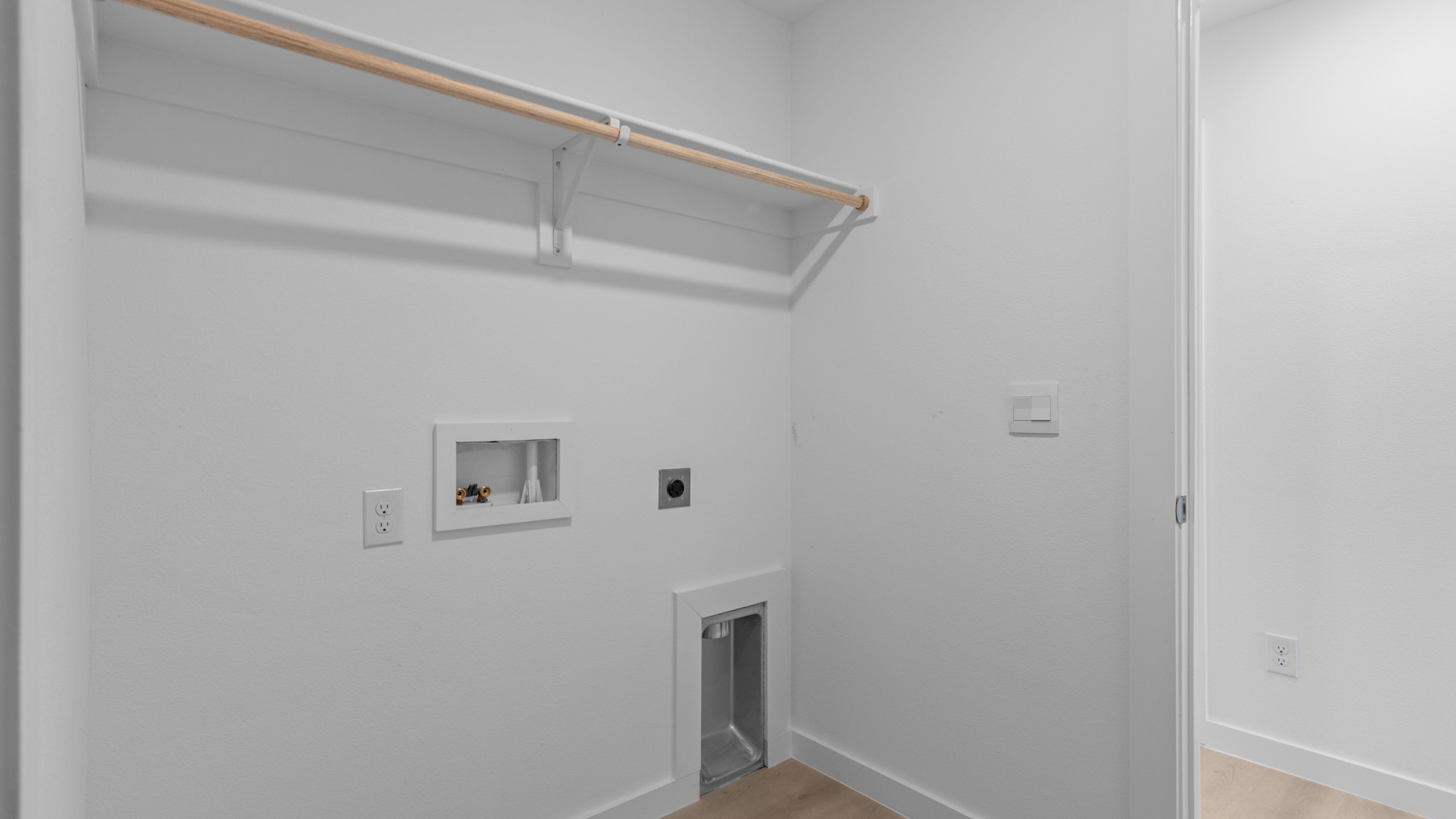 Laundry and utility room with wooden shelving just off the entry way