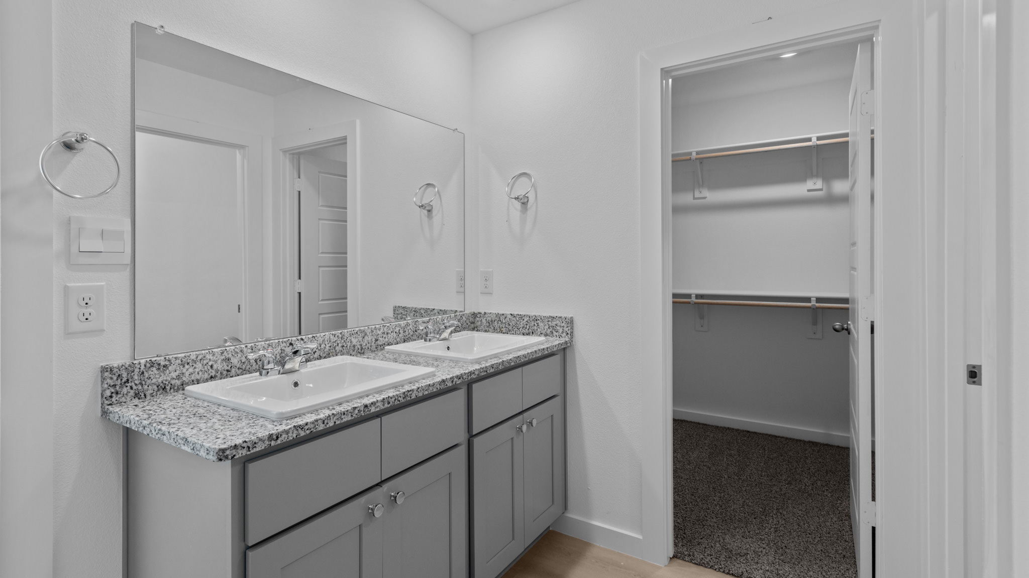 Primary bathroom with dual sink, vanity, grey cabinets and attached closet