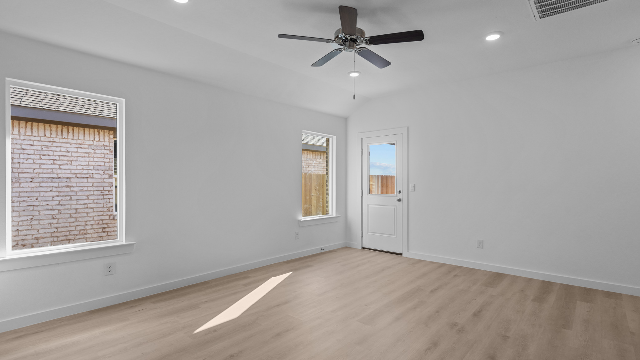 Living area with windows for natural lighting, ceiling fan and white interior