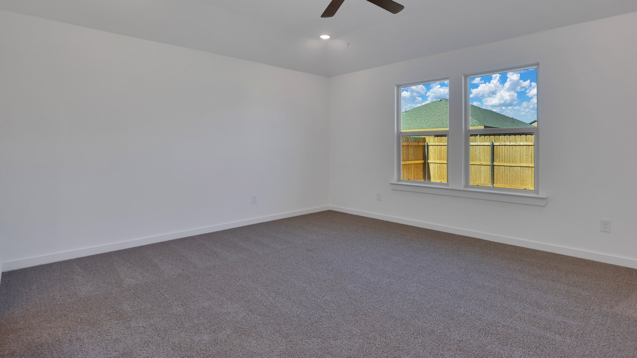 Primary bedroom with double windows and plush carpet floors