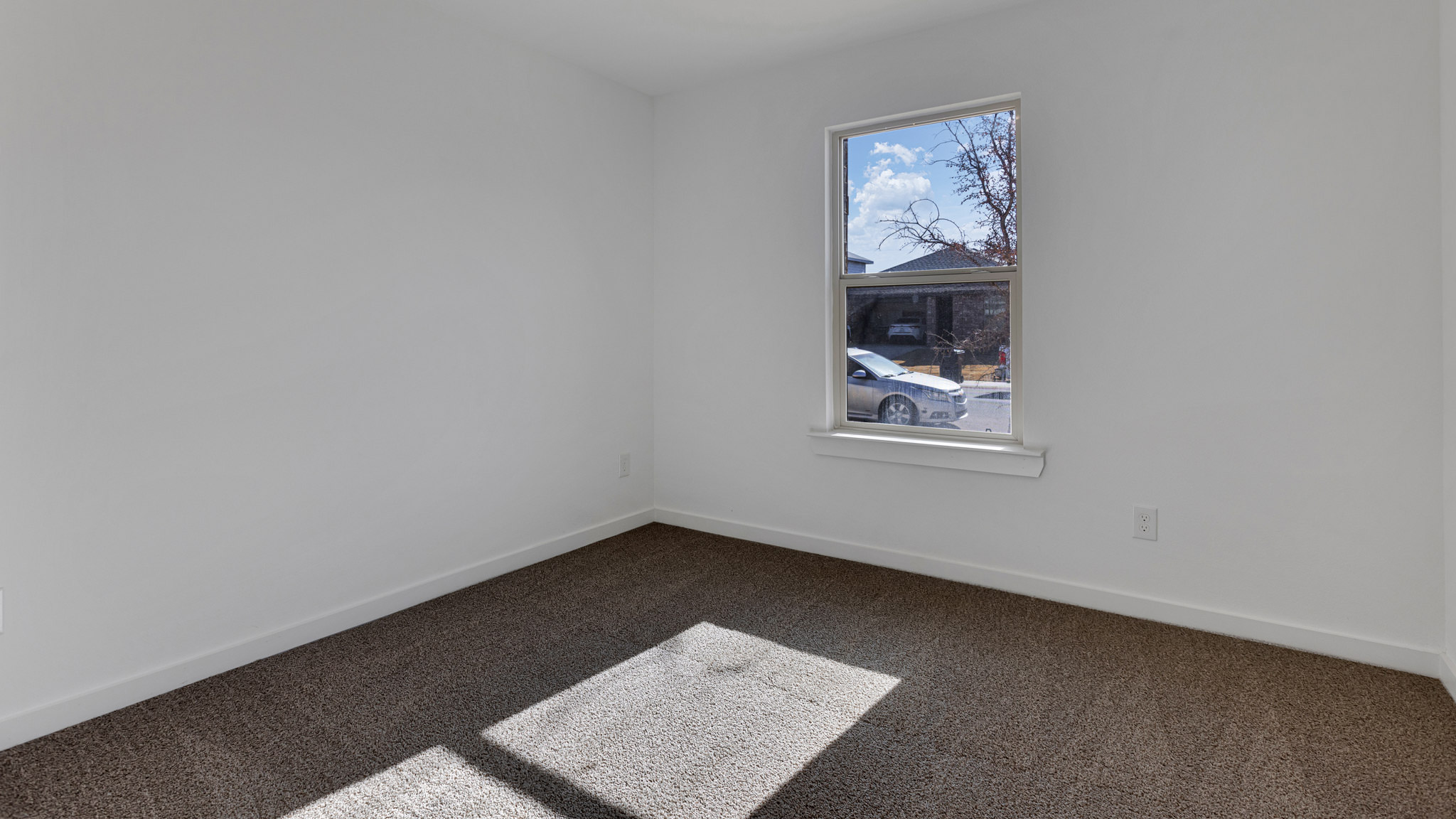 Bedroom 1 with front window and plush carpet floors