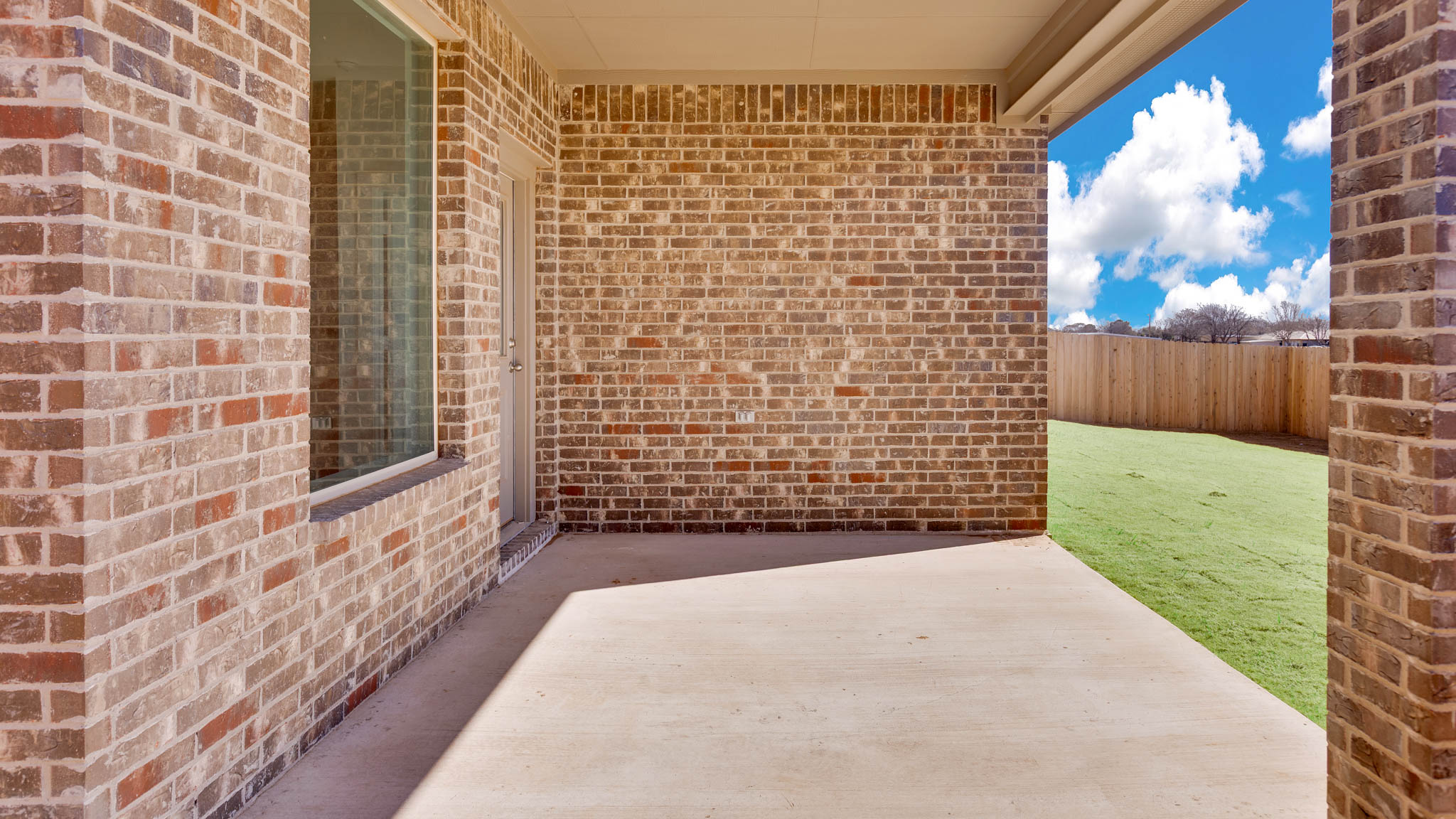 Covered back patio area overlooking spacious backyard